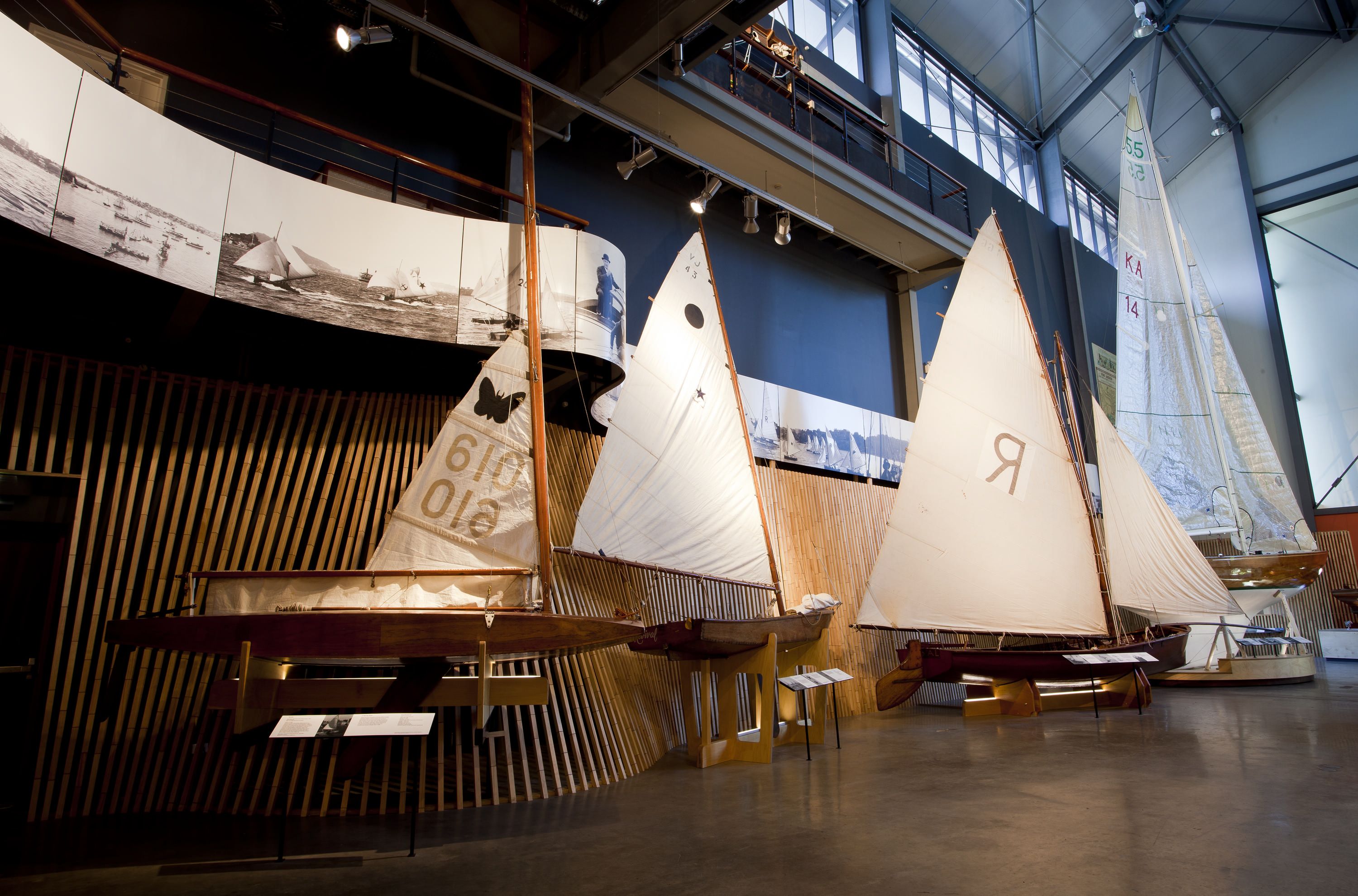 Photo showing a museum gallery with small wooden sailing ships. 