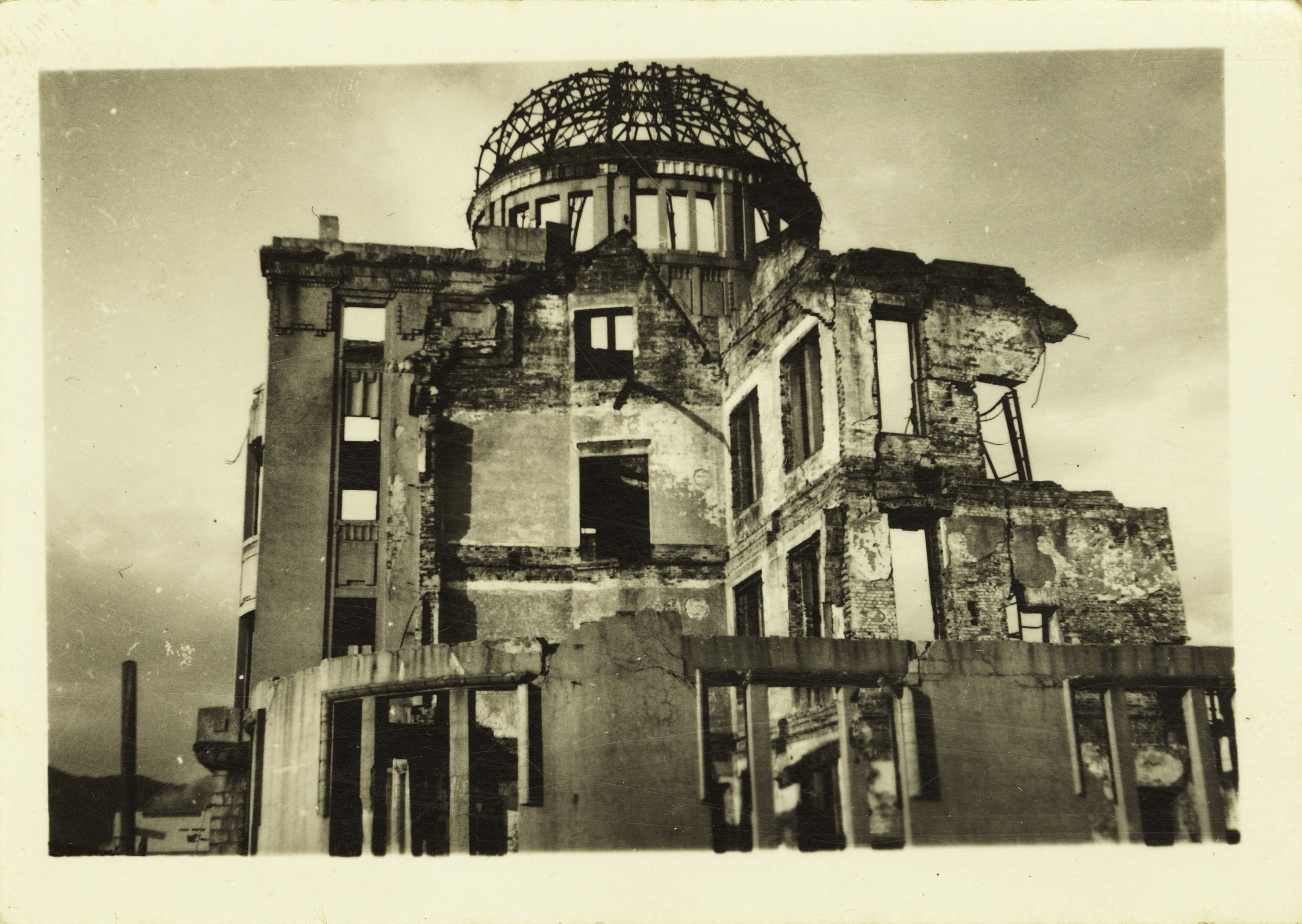Black and white photograph on yellowed paper of ruined Hiroshima Dome.