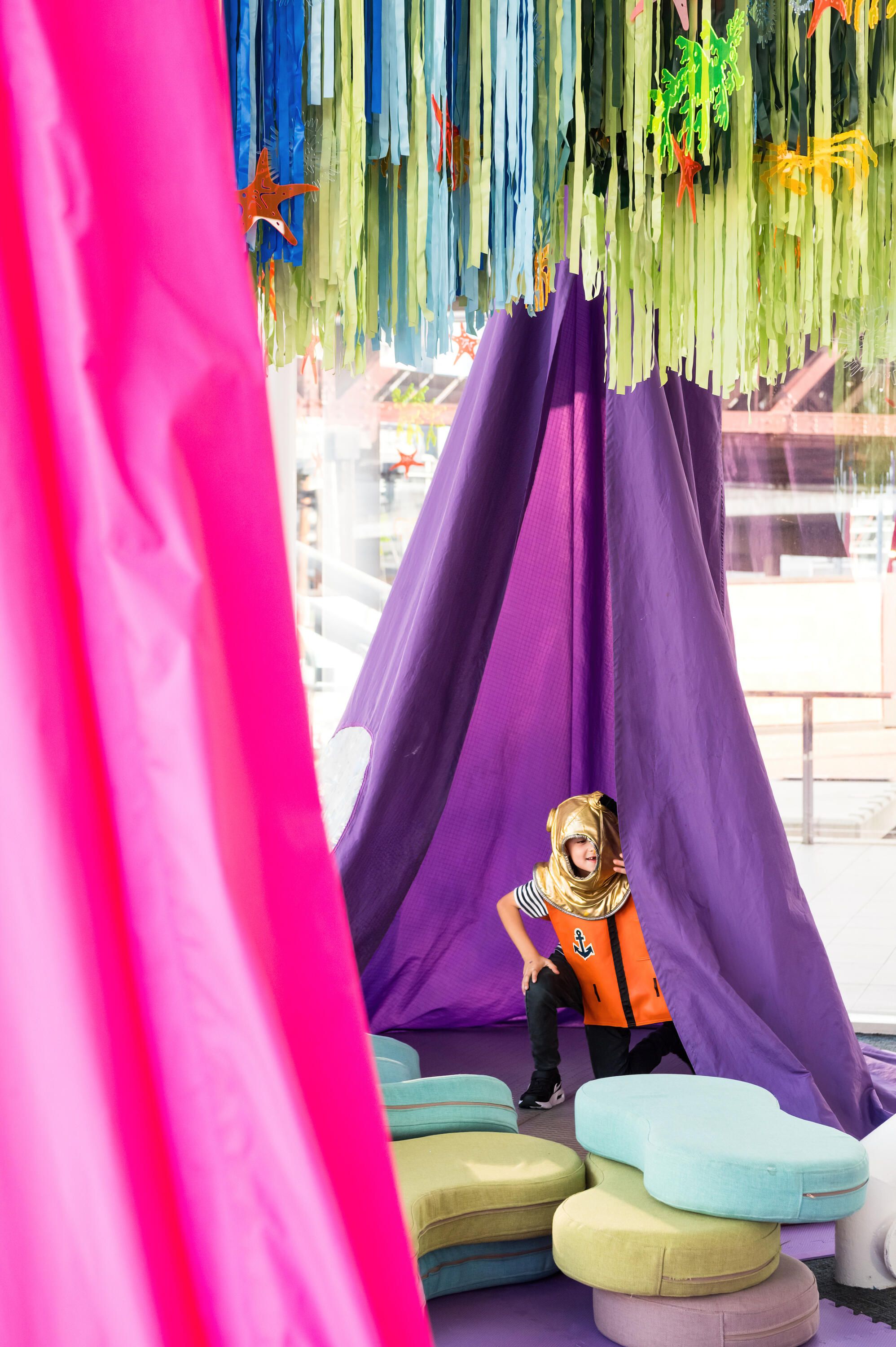 Child wearing a gold diving helmet and orange life jacked dress up.