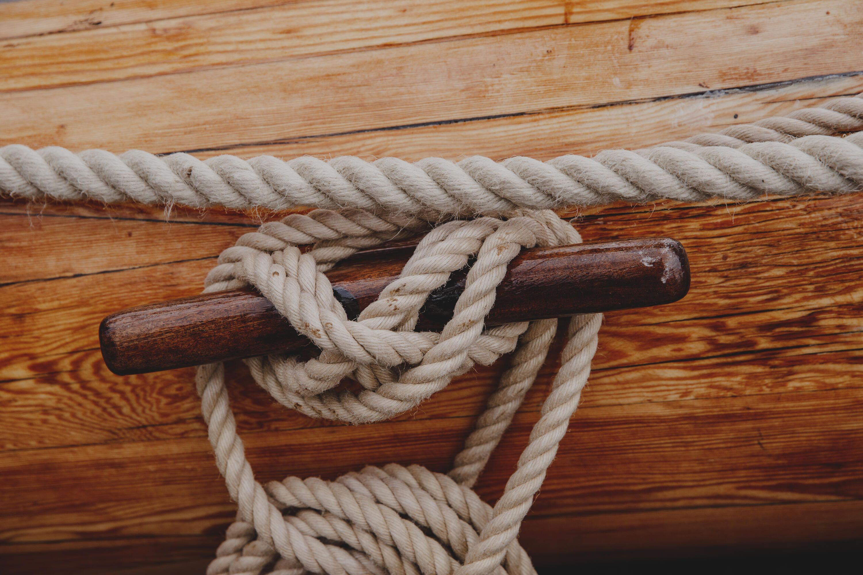 Close up photo showing ropes on the side of a wooden ship.