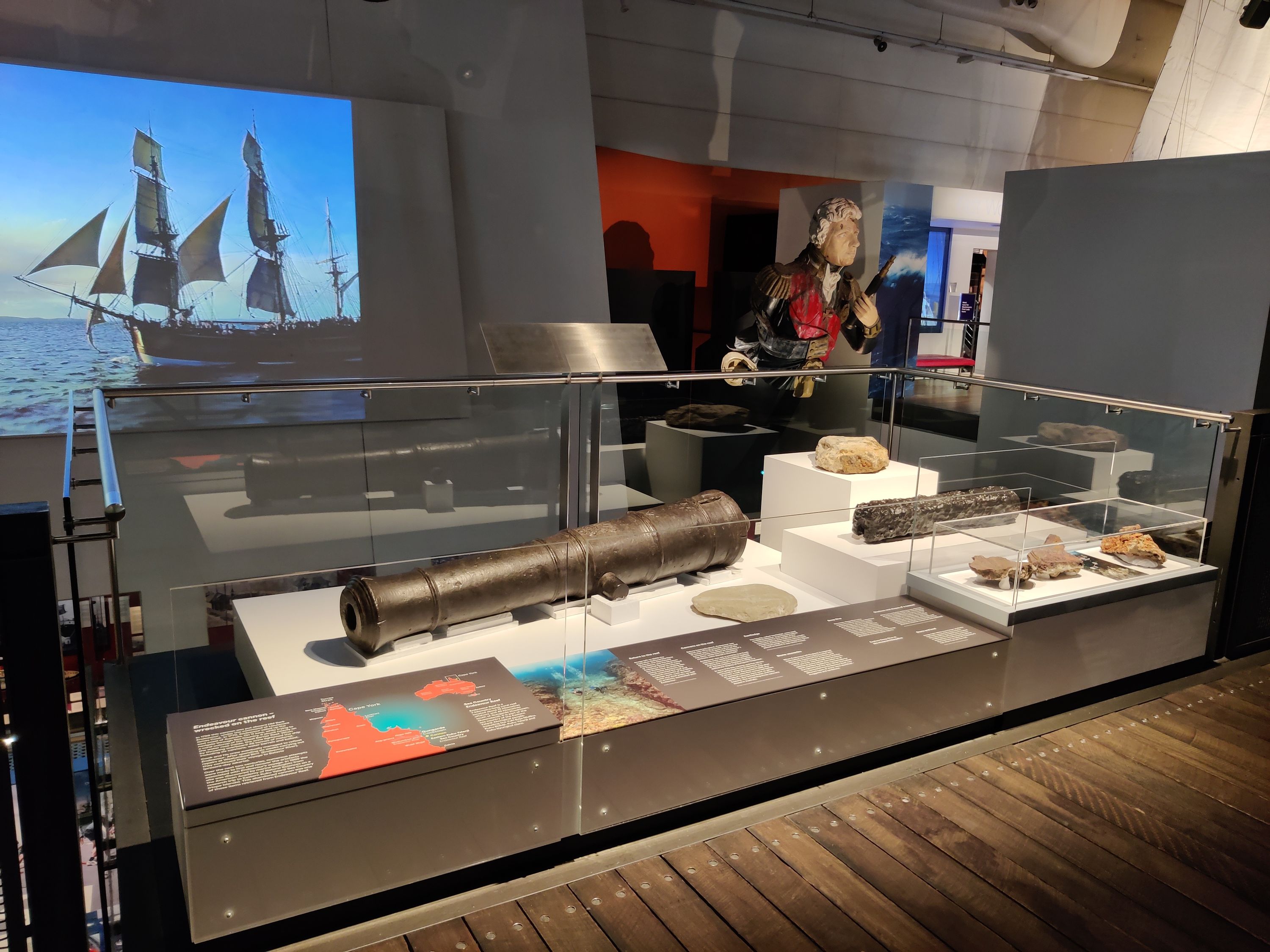 Photo showing a museum display featuring a metal barrel of a small cannon.