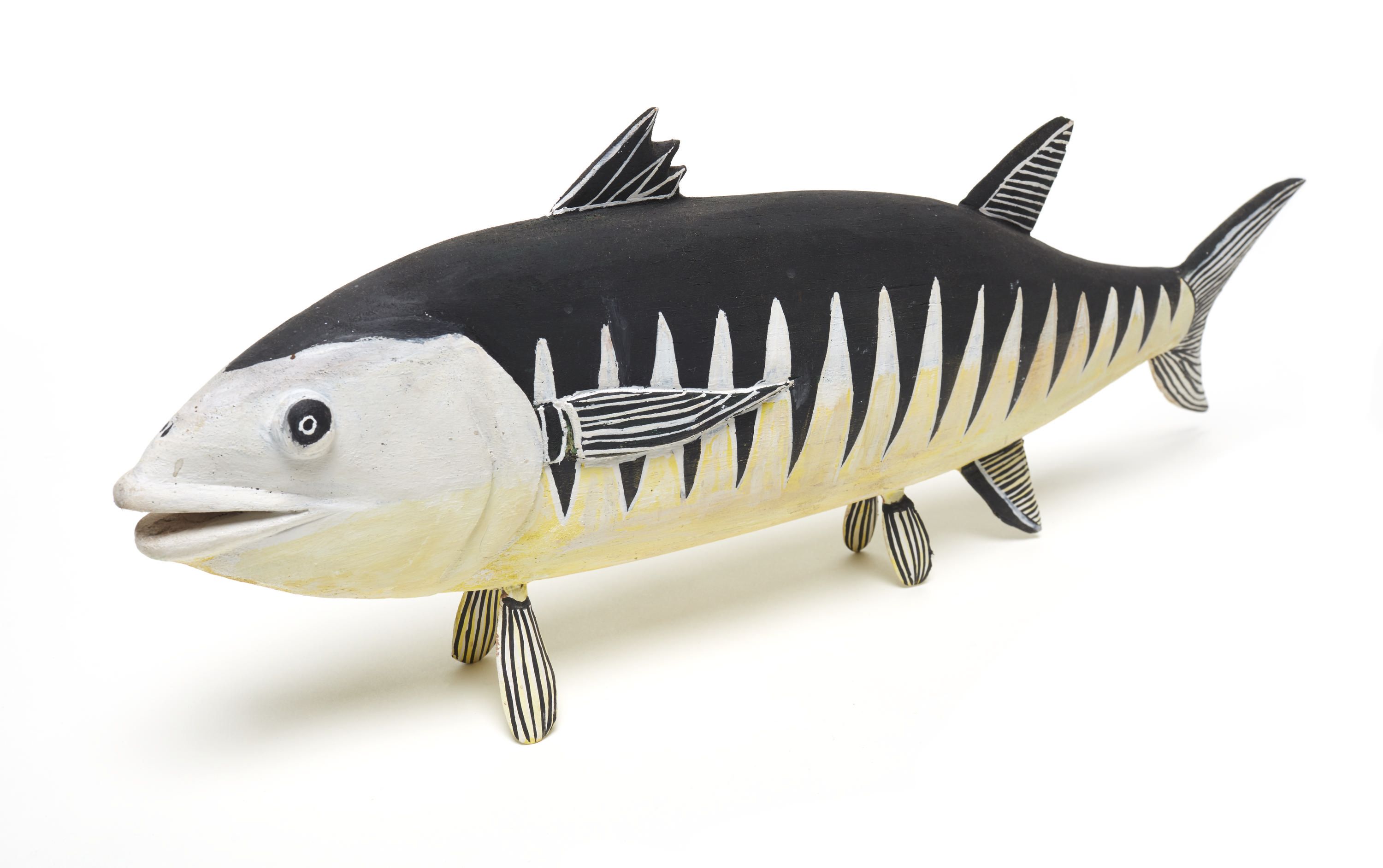 Photo of a carved sculpture of a fish, painted with black and white pattern. 
