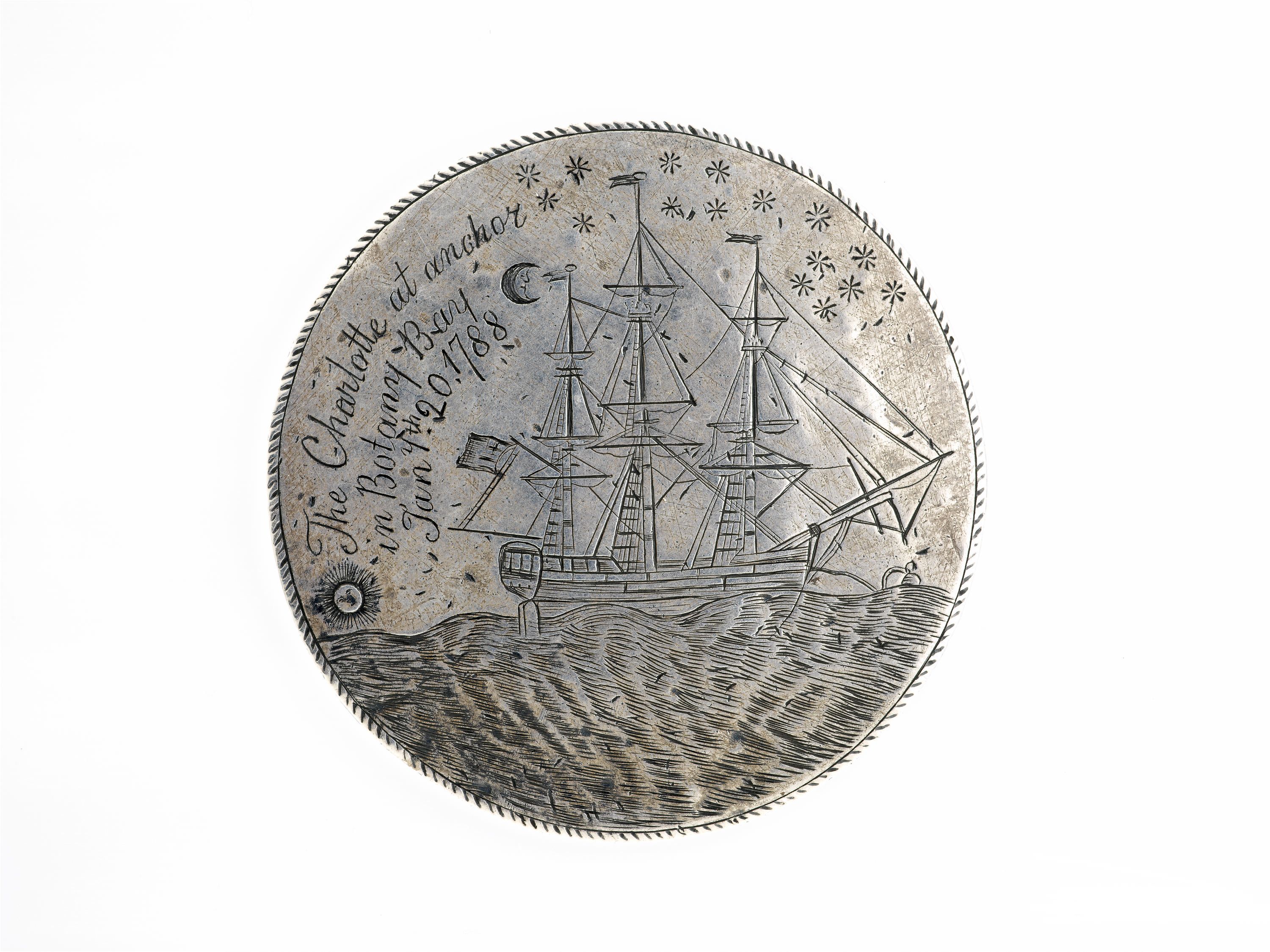 Photo of a silver disc engraved with a fully-rigged ship, the sun is near the horizon line on the lower left whilst a crescent moon and stars are inscribed on the upper right. Above the sun in the upper left field are inscribed the words 'The CHARLOTTE at anchor / in Botany Bay / Jany. th 20, / 1788'.