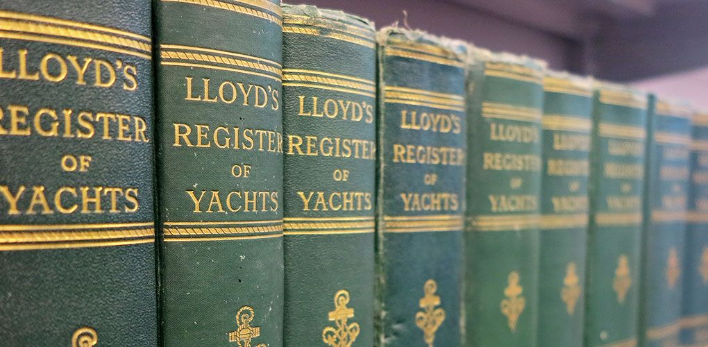 Close up photo showing a line of books with green covers and gold lettering saying "Lloyd's register of yachts"