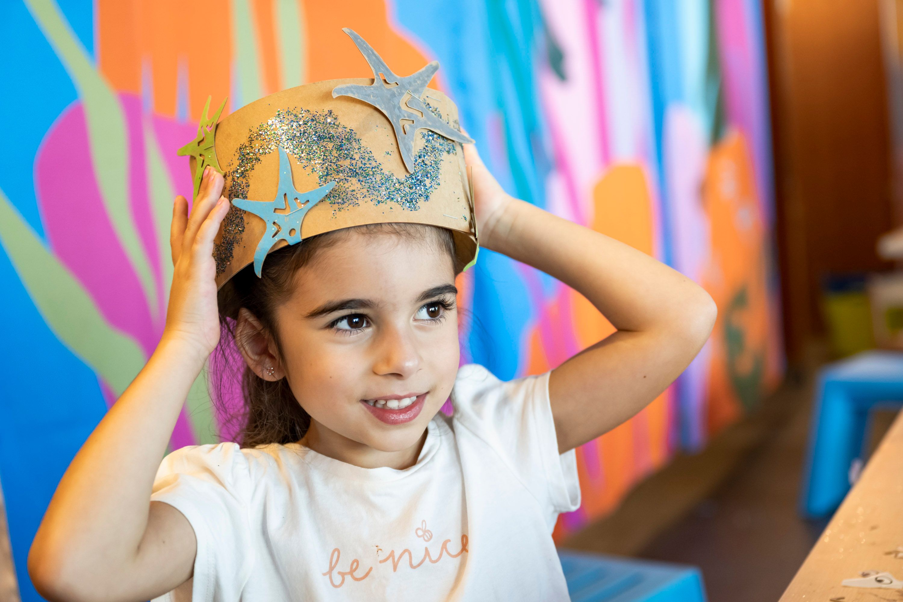 Photo of a girl wearing a cardboard crown decorated with glitter and starfish shapes