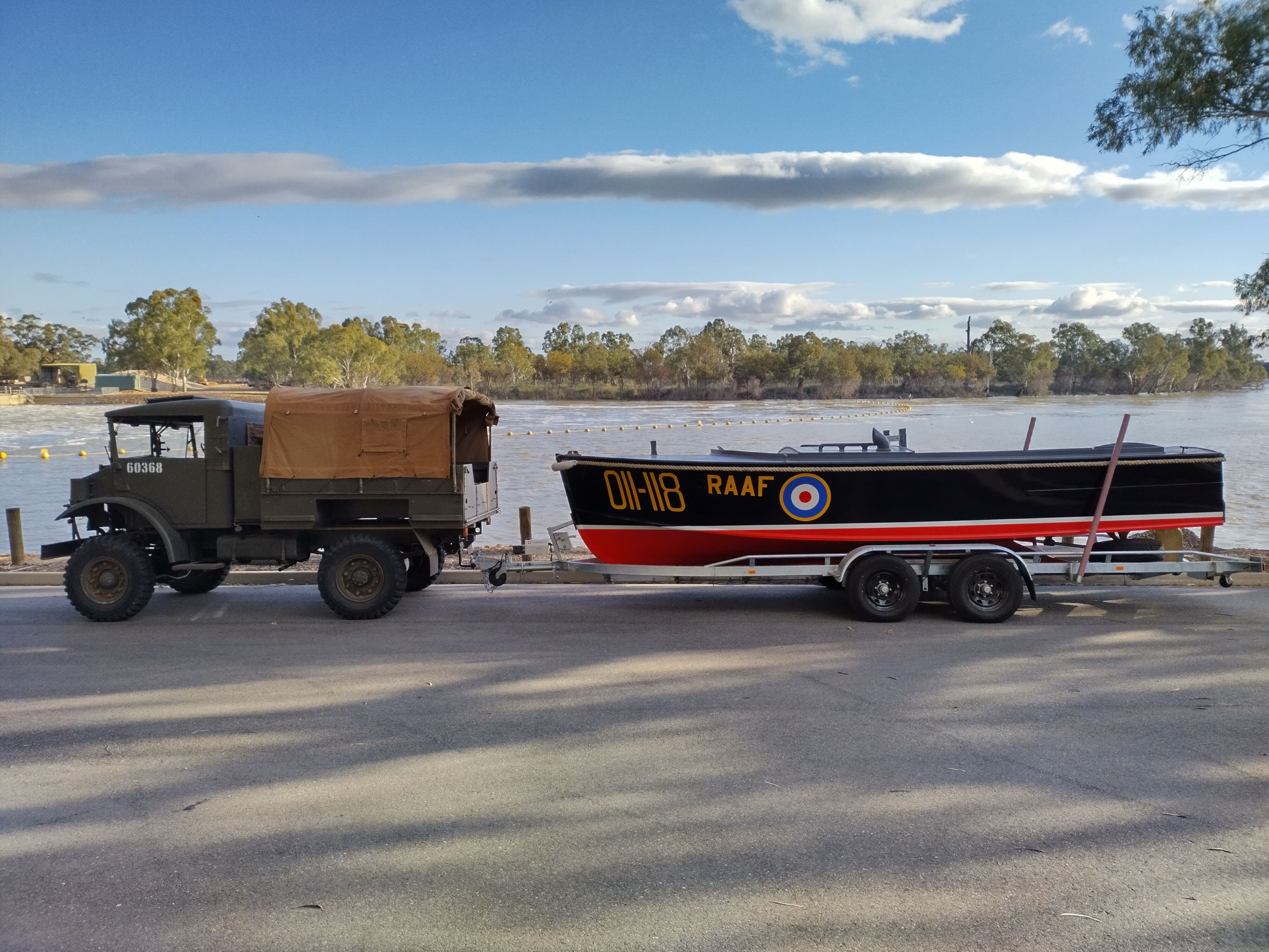 Photo showing a milirary truck towing a black and red boat on a trailer