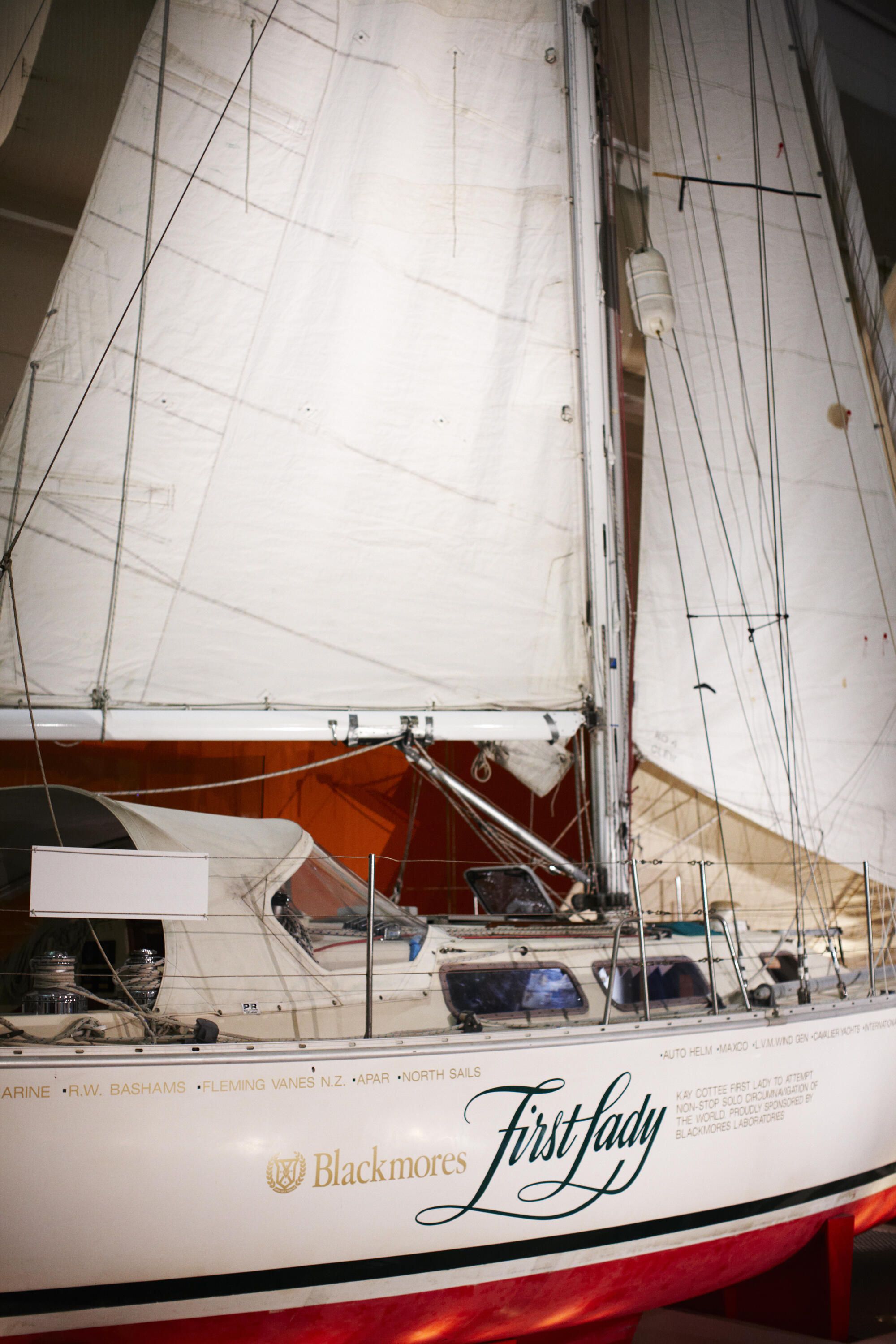 Close up photograph of a sailing yacht with white sails inside a museum building. 