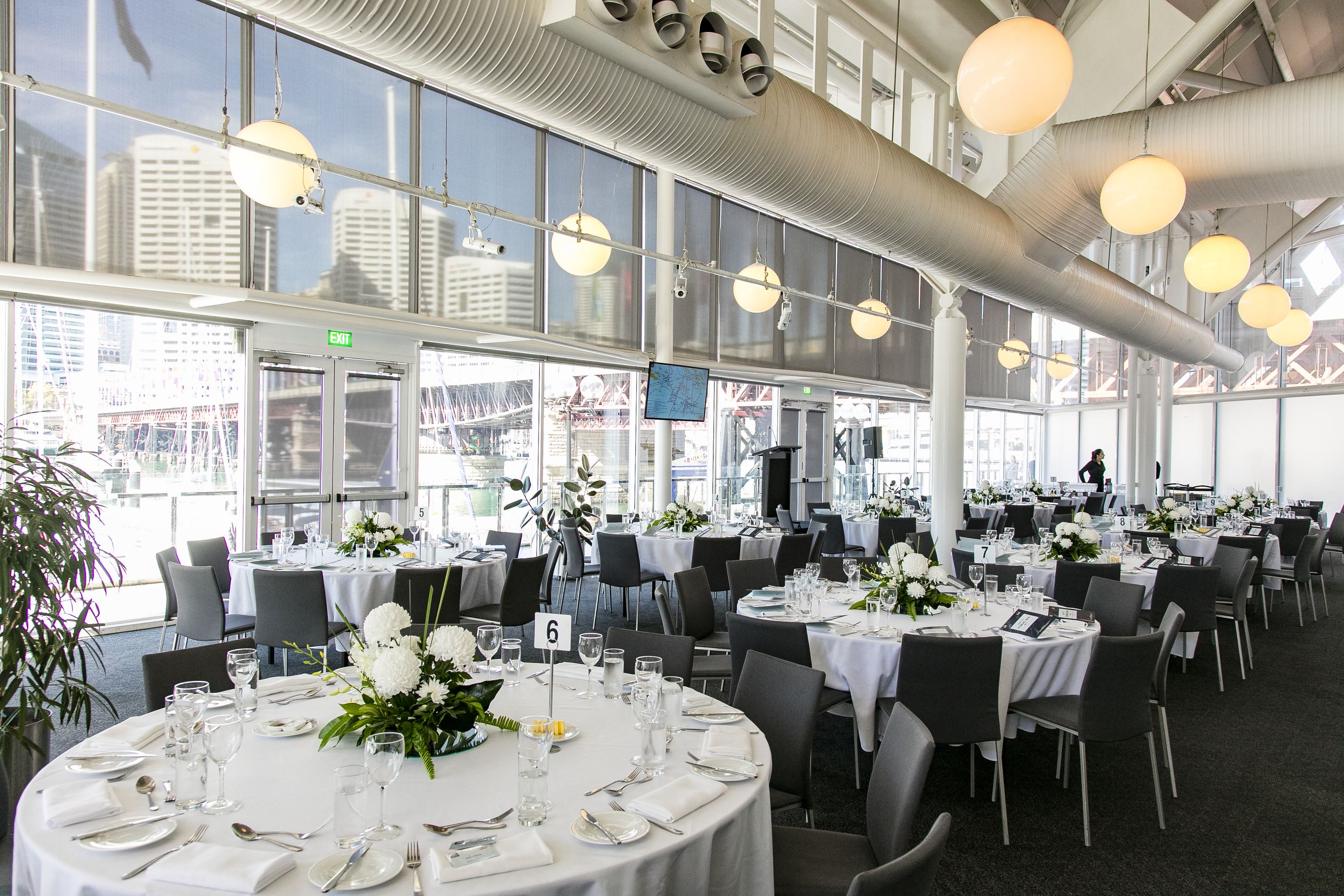 photo of a light filled event space with large round tables set for a formal event. 
