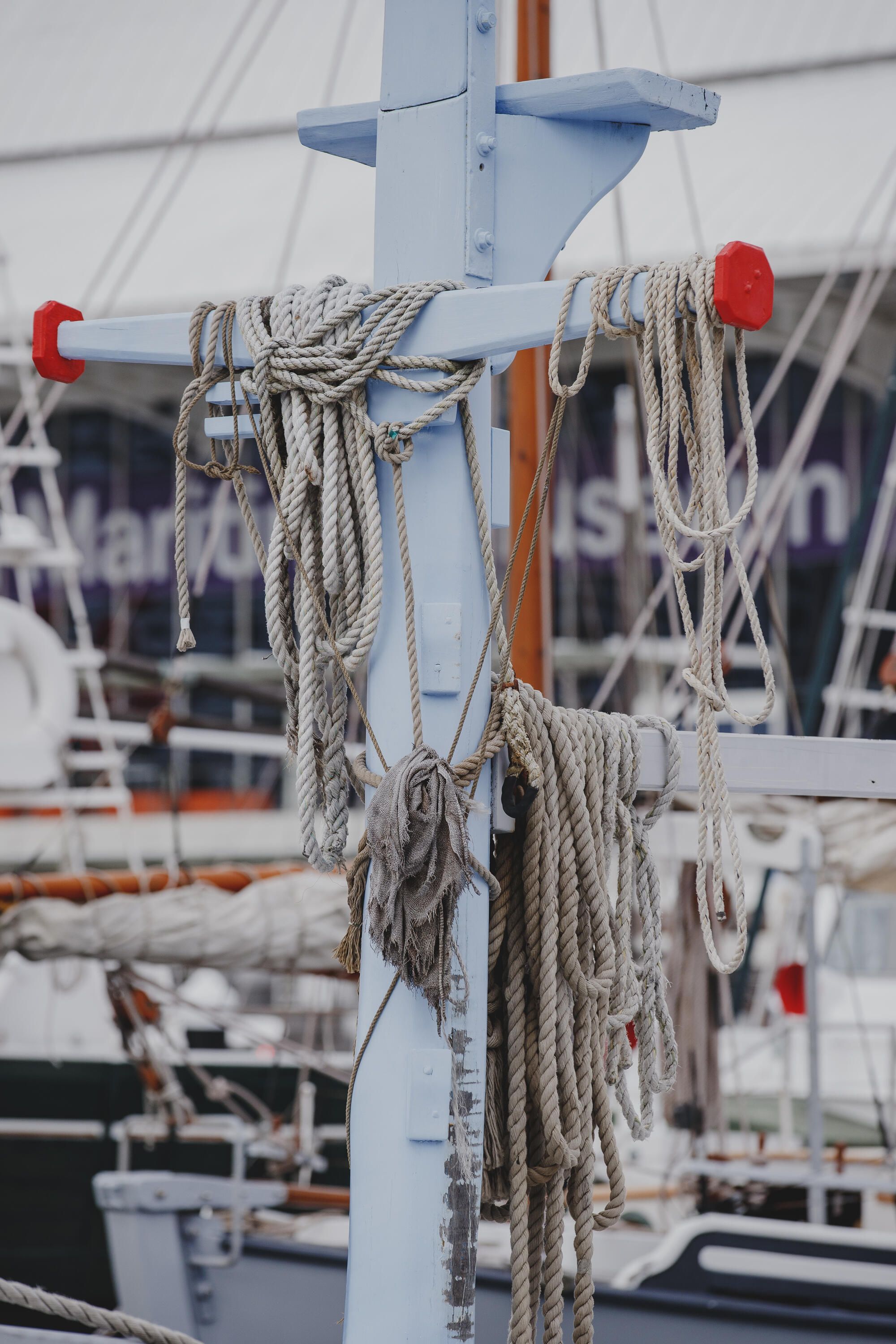 Close up photograph of a wooden boat showing mast post with ropes slung over it.