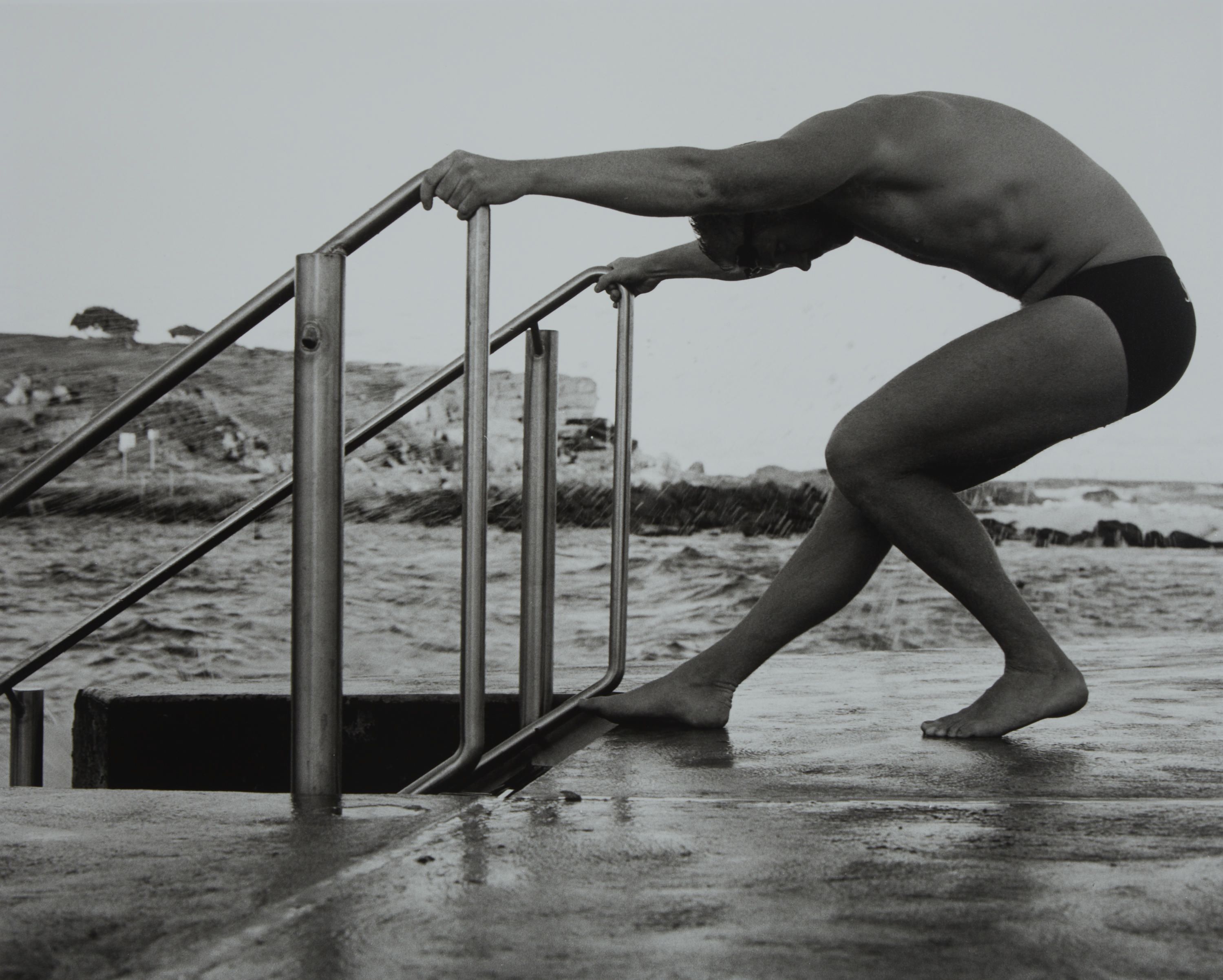 black and white photograph of male swimmer about to enter an ocean pool