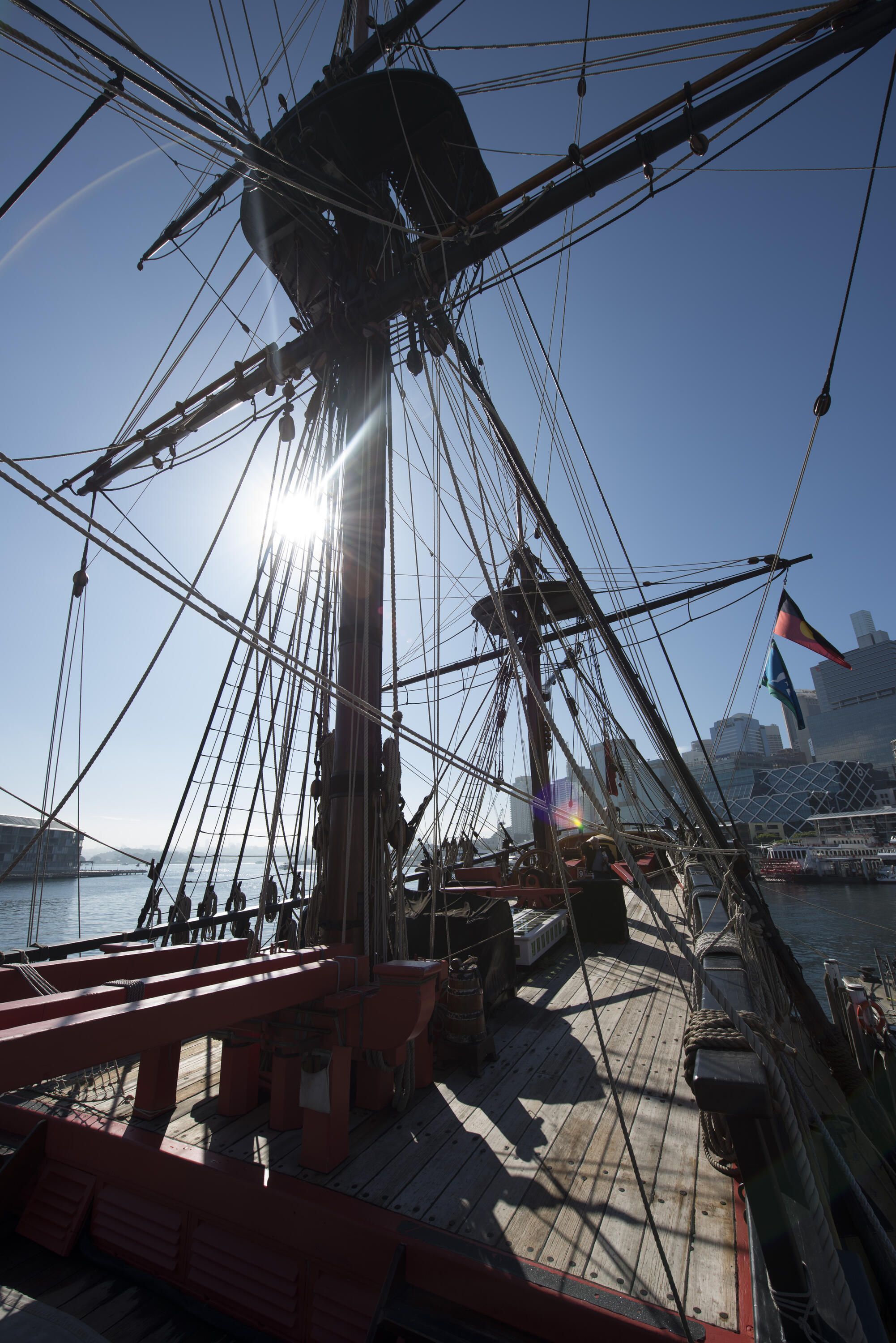 photo on the deck of a tall ship, looking up at the mast with a blue sky.