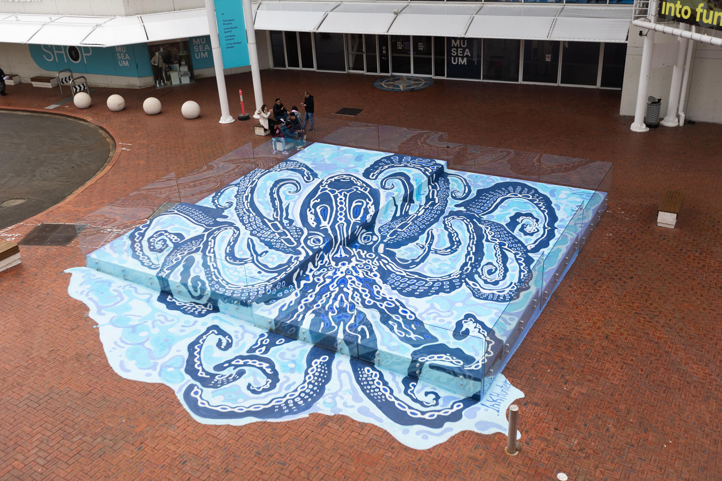 Photo looking down on a large mural or a blue octopus.