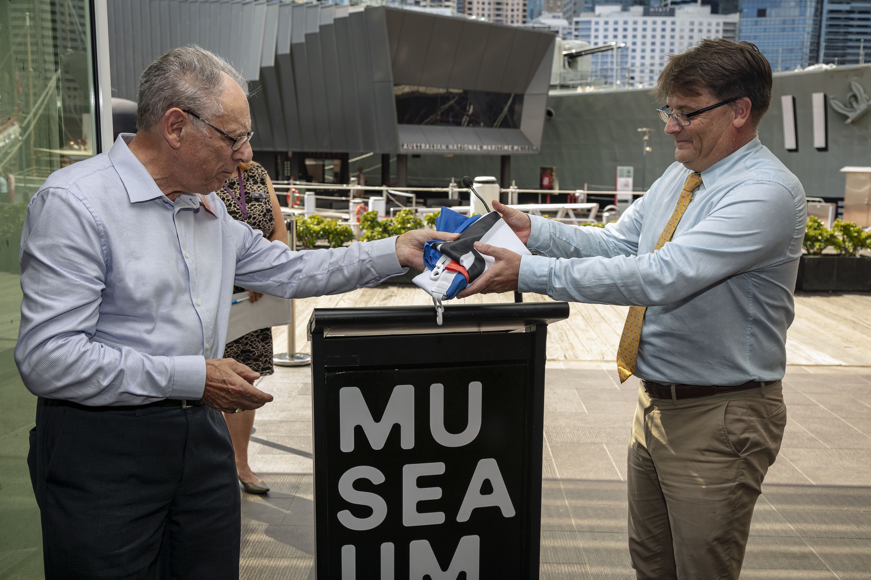 Two mend handing a folded flag between them.