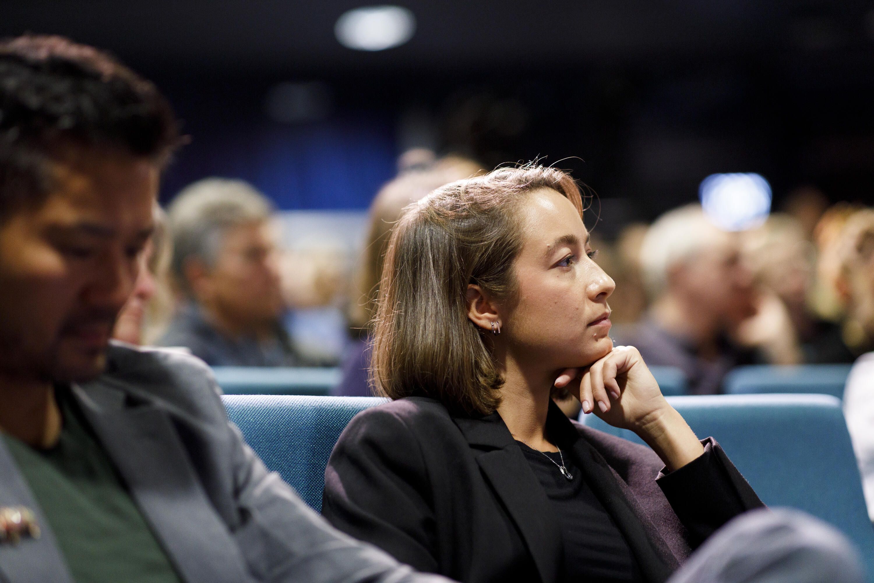 Photo of a woman with short, dark hair , in a theatre. 