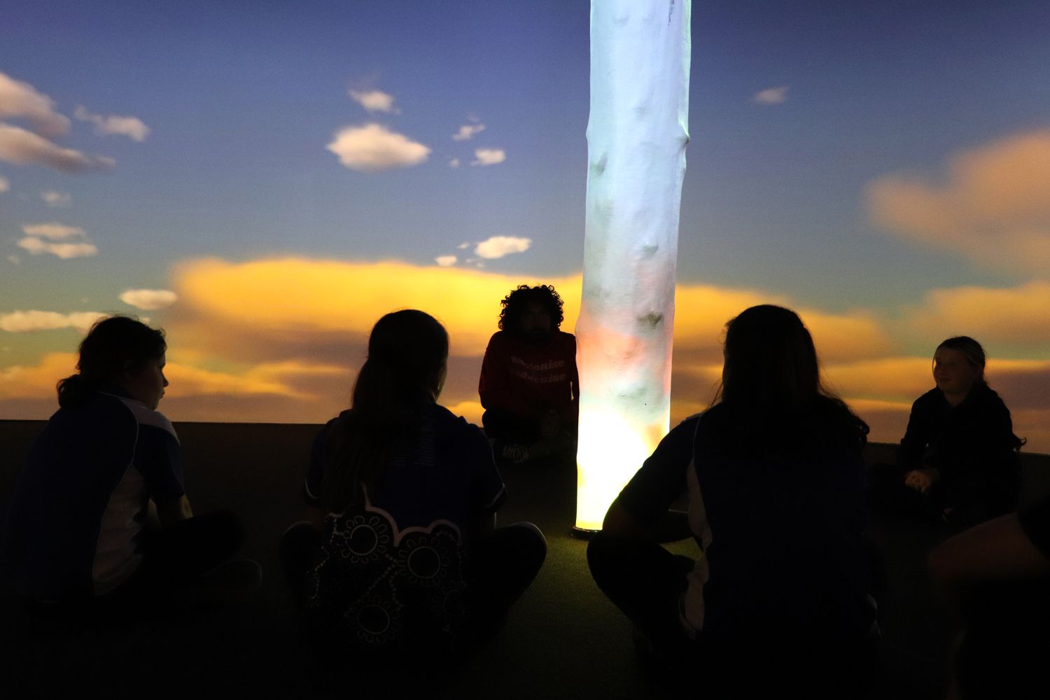 Students silhouetted with a projection of a sunrise in the background.