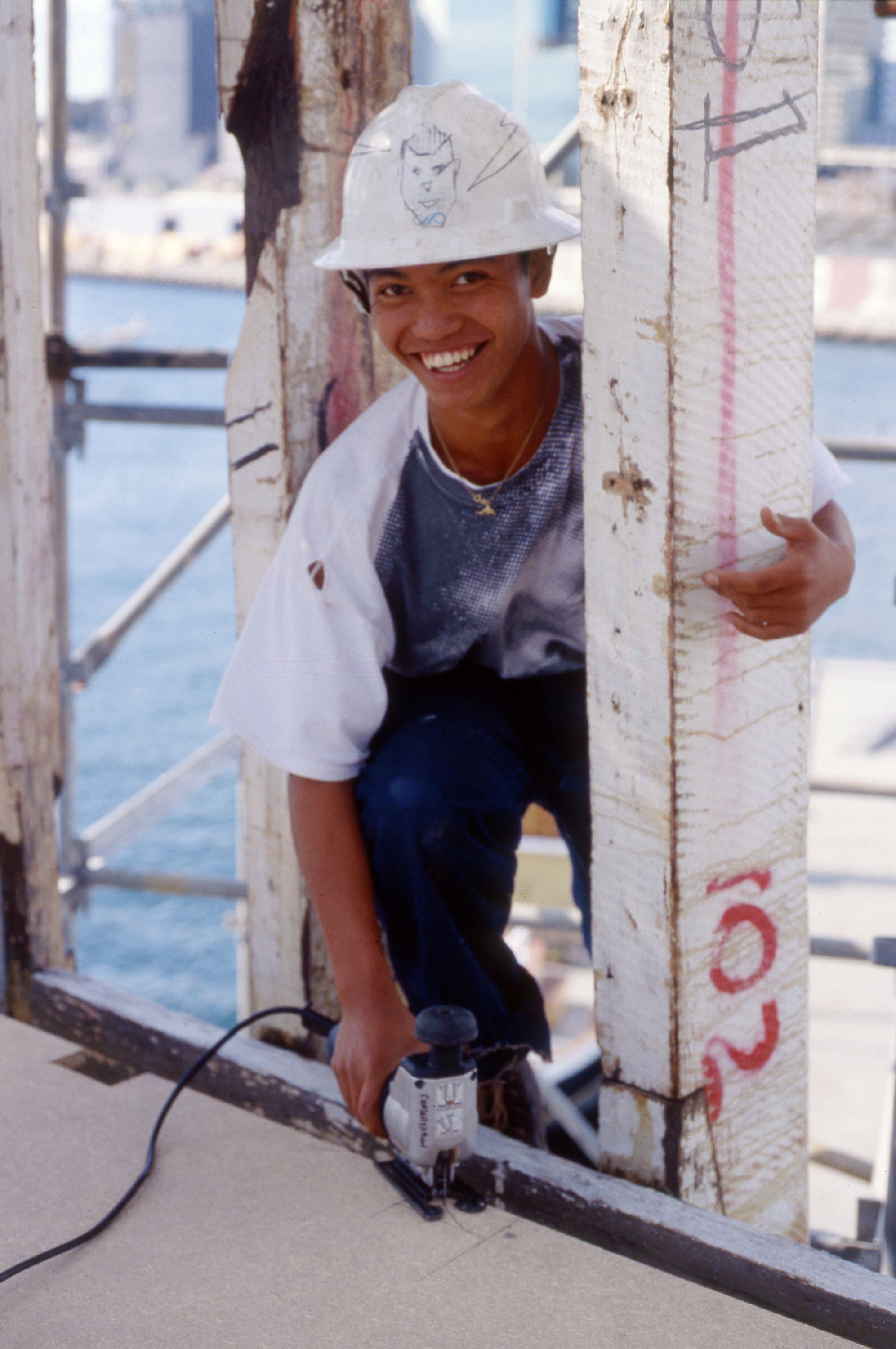 Photo of a young man wearing a hard had at work, pictured holding a jigsaw tool.