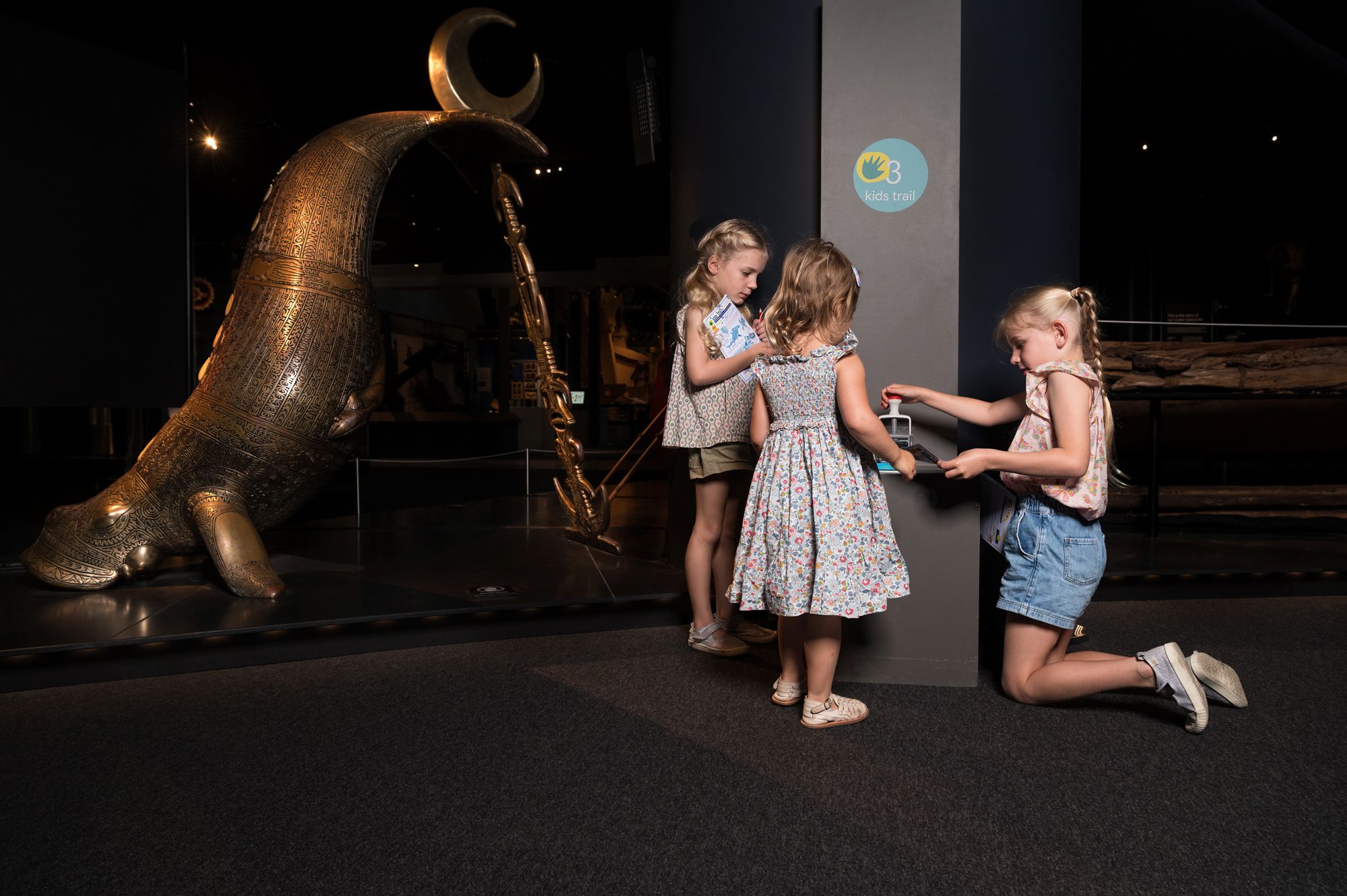 Photo of 3 young girls stamping a paper booklet in the gallery