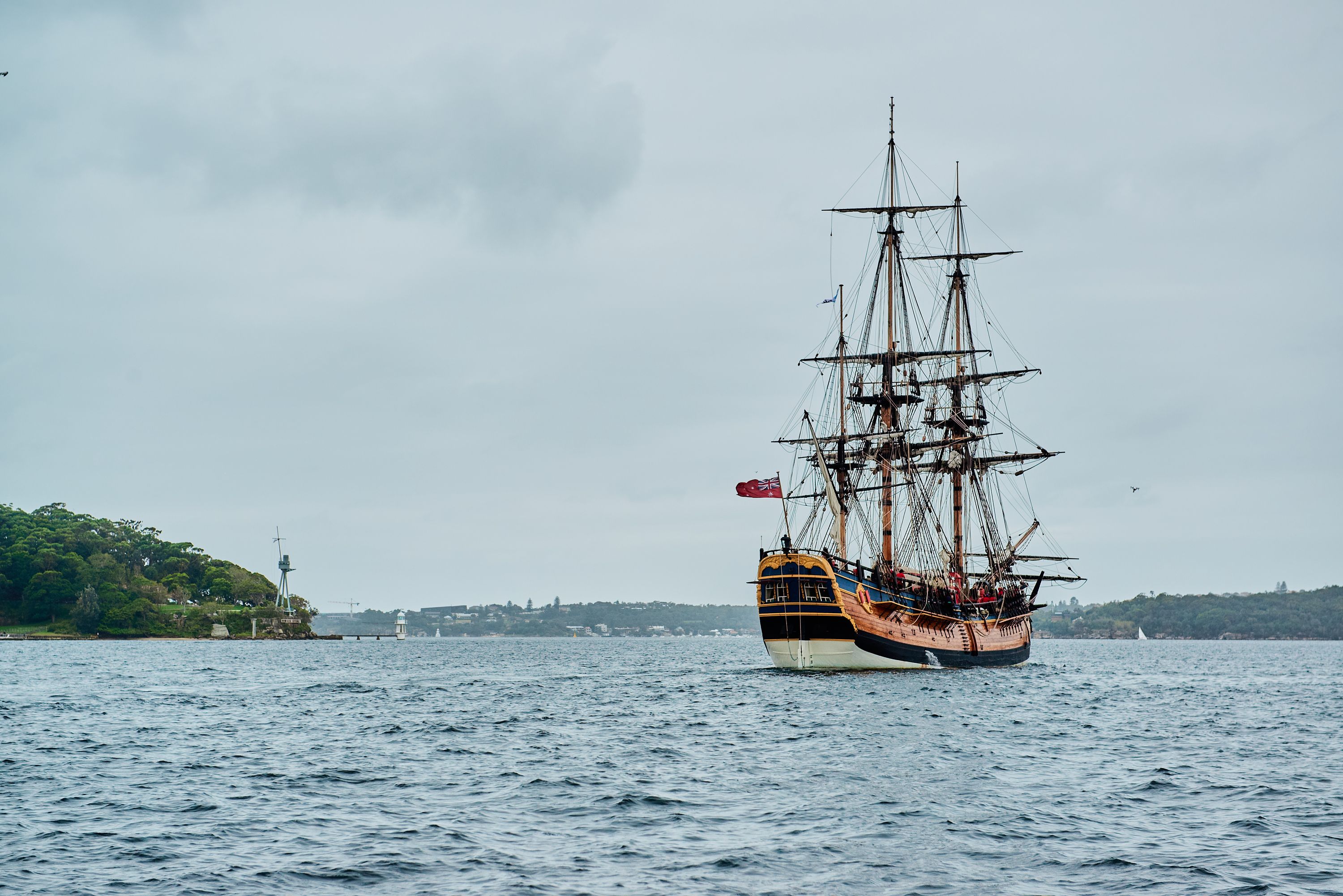 Photo taken from behind showing a wooden tall ship in a harbour