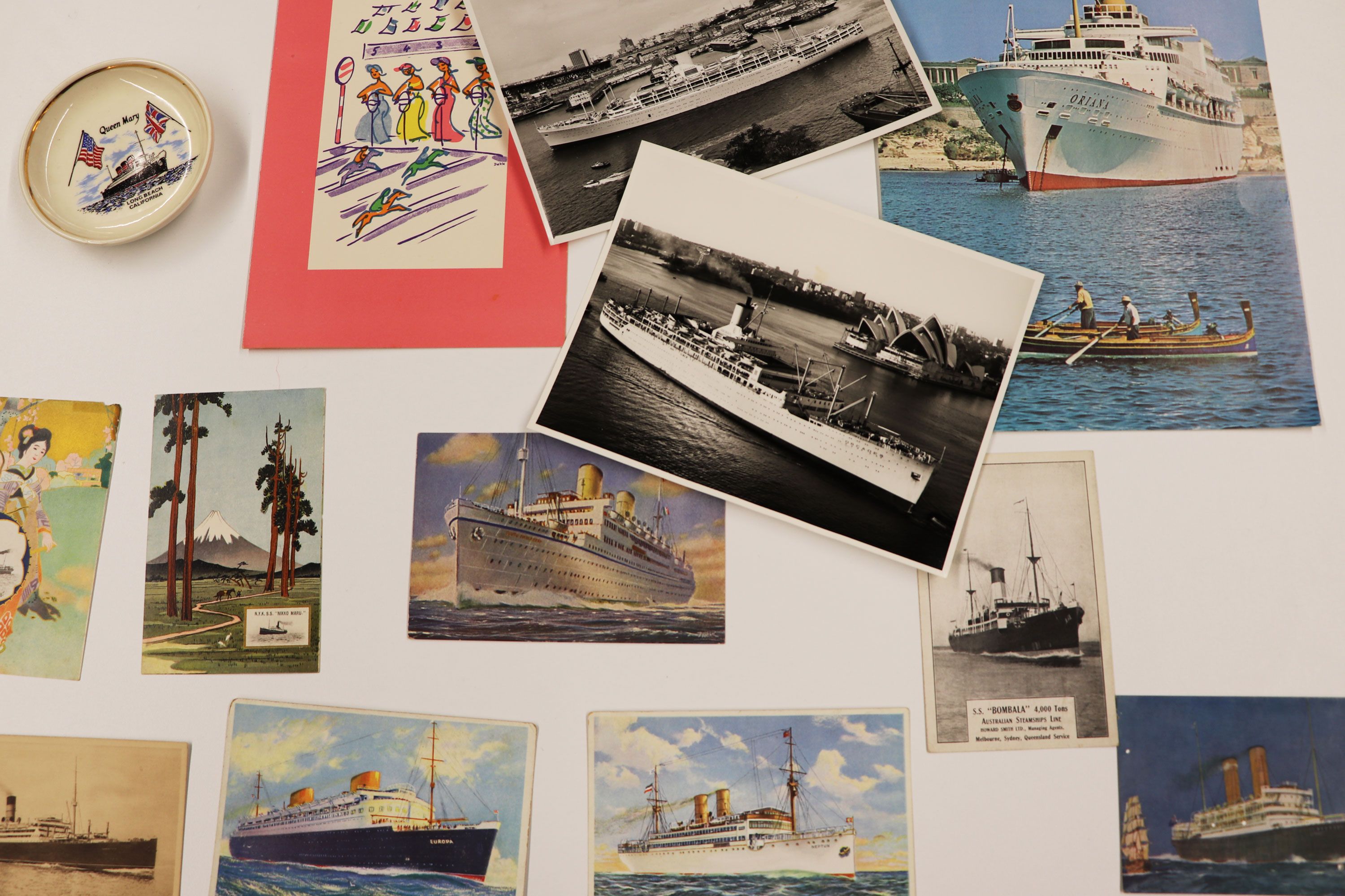 Selection of photos, postcards and illustrations on a white table.