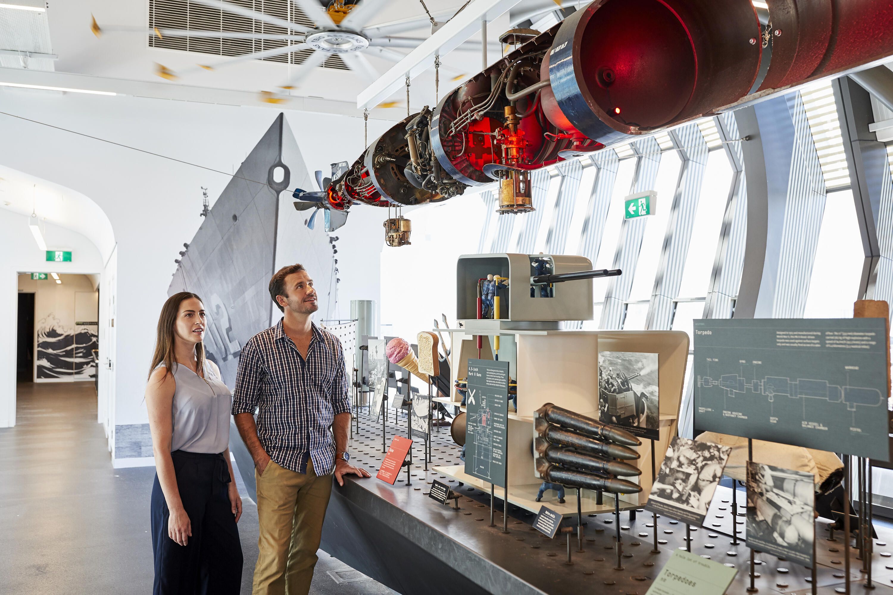 Photo showing two museum visitors (a young adult couple) inside Action Stations Navy exhibition