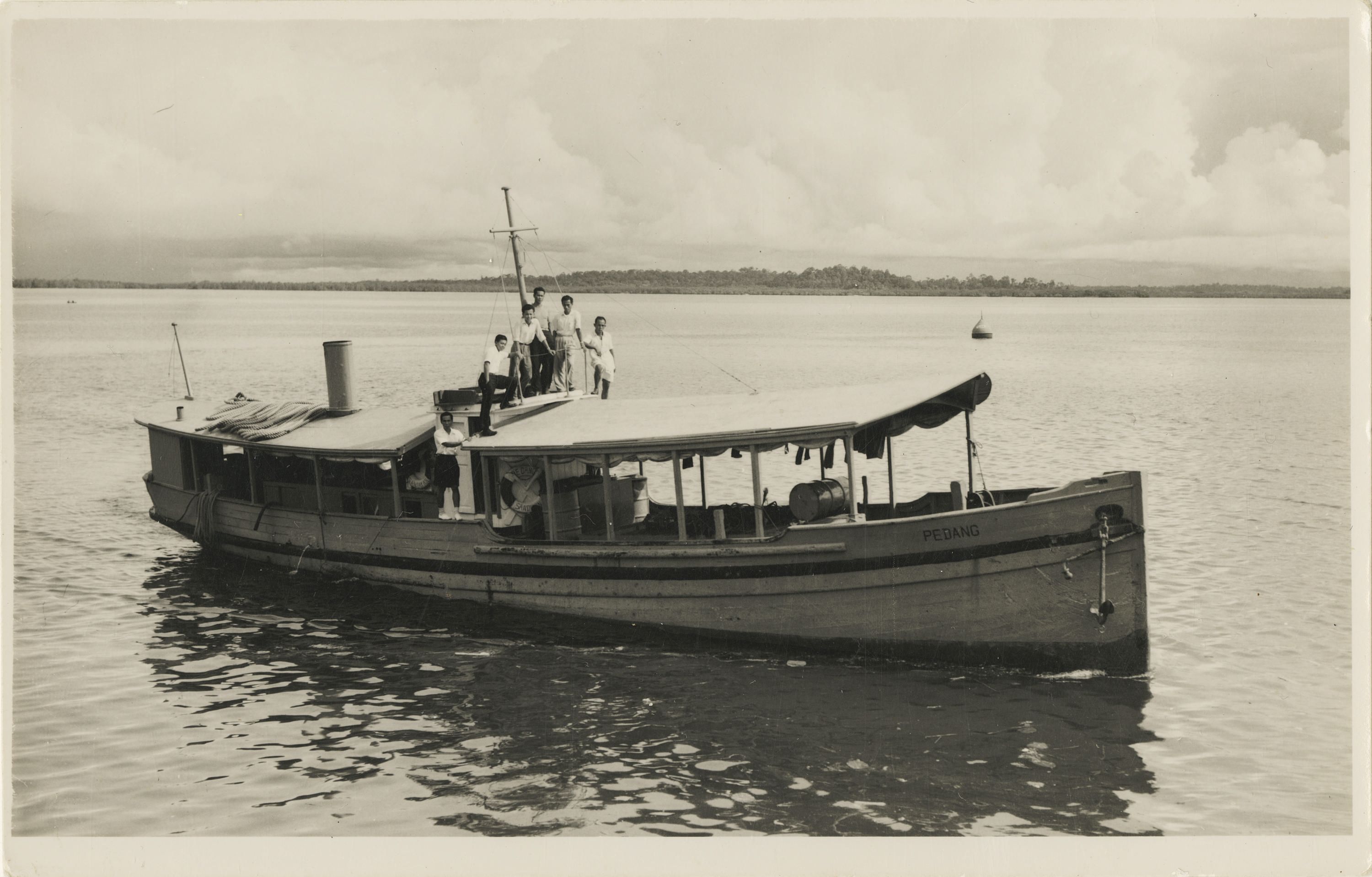 a black and white photograph depicting a starboard side view of ML PEDANG with five people standing on the cabin roof and two more people inside