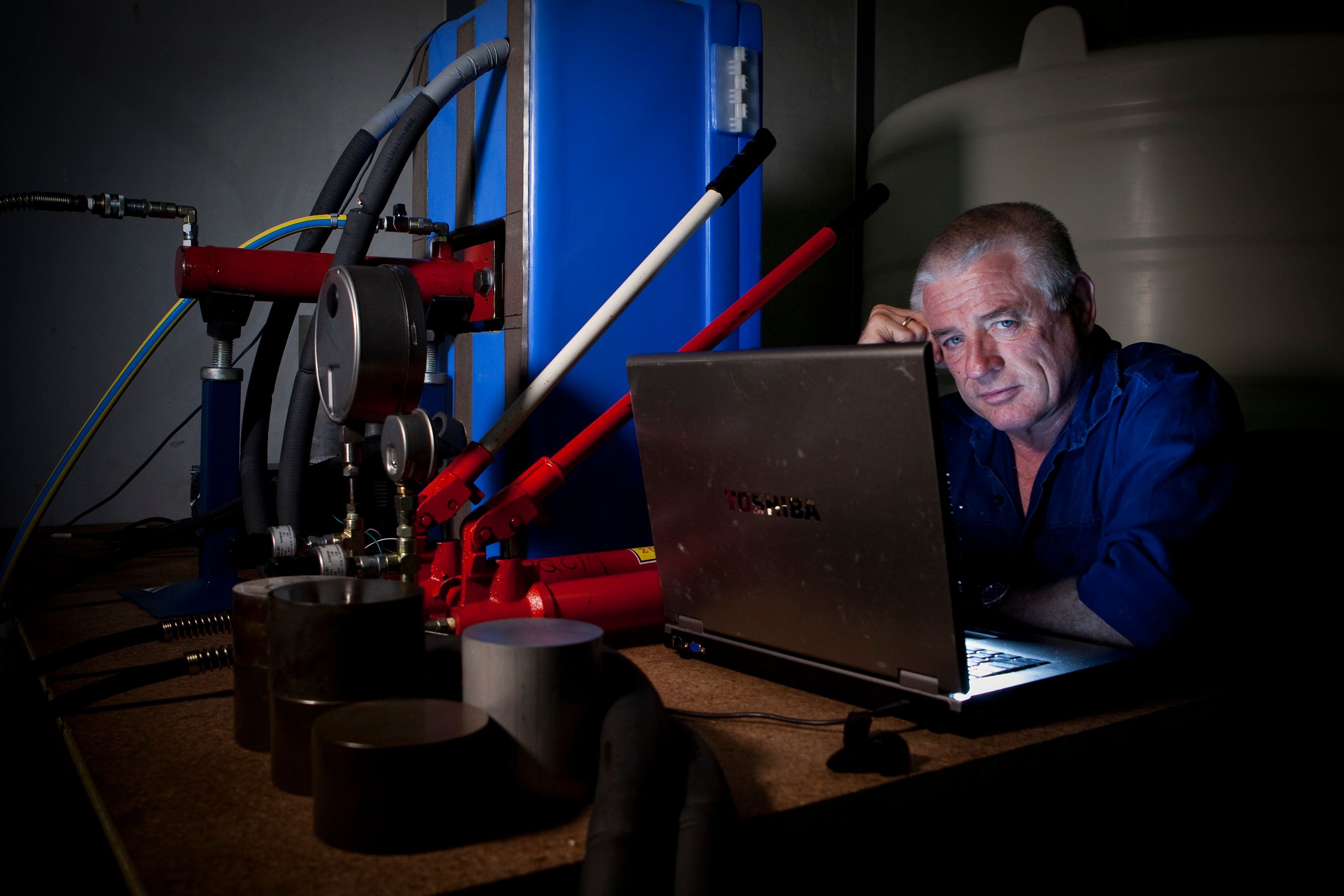 Photo of a man sitting behind a labtop computer, looking at the camera.
