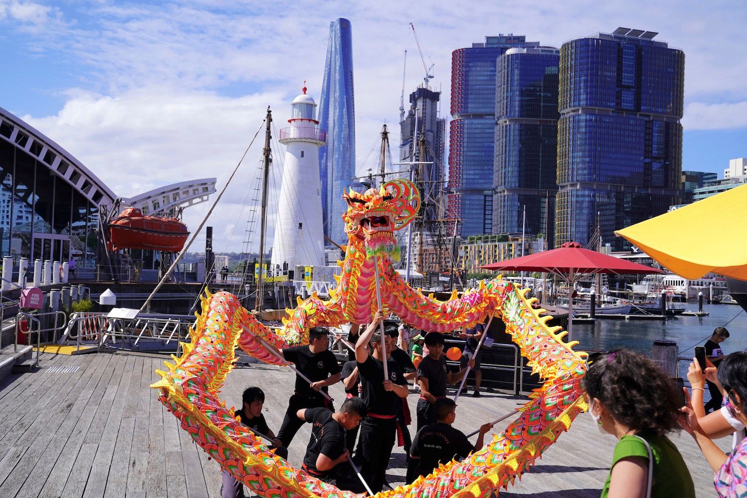 Photo of a colourful, Chinese dragon controlled by a group of people wearing black.