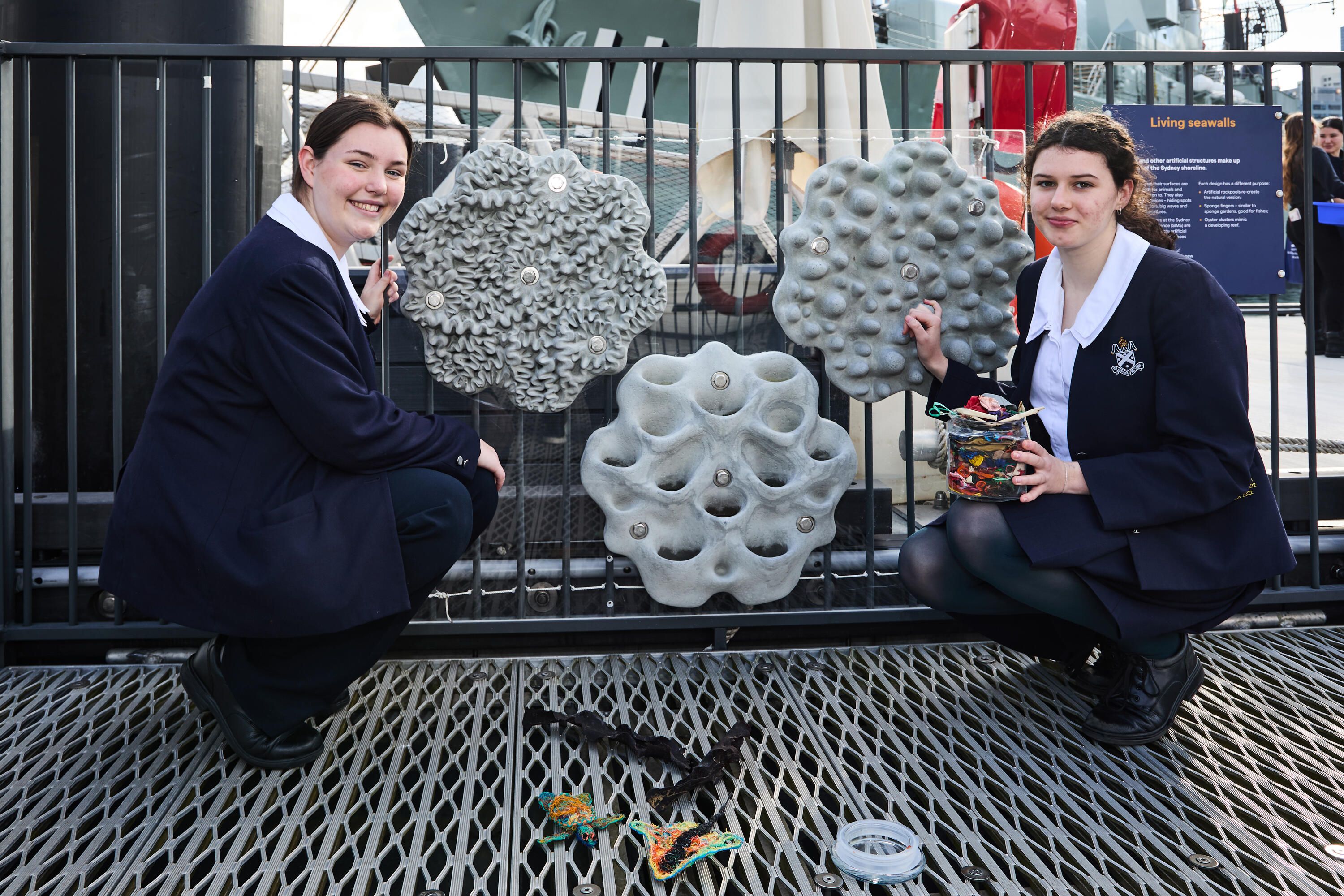 Photo of 2 high school girls looking at a display of artificial rock walls.