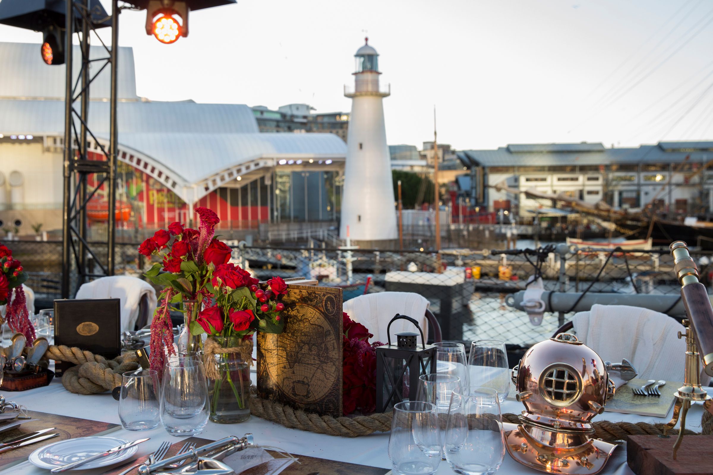 Photo with a table set for an event in the foreground and a white lighthouse in the background.