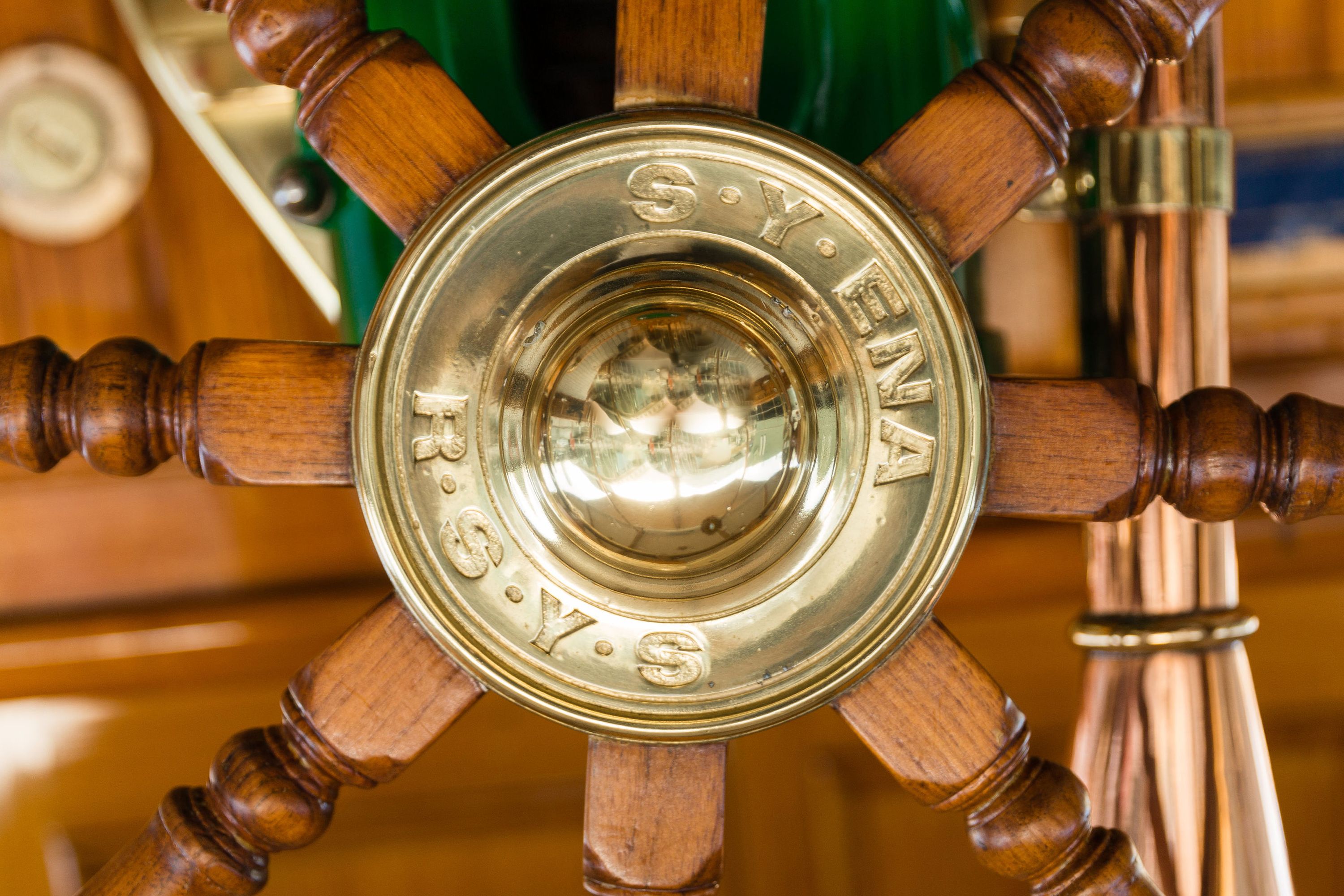 Close up photo of a ships wheel, with engraving S.Y. ENA R.S.V.S