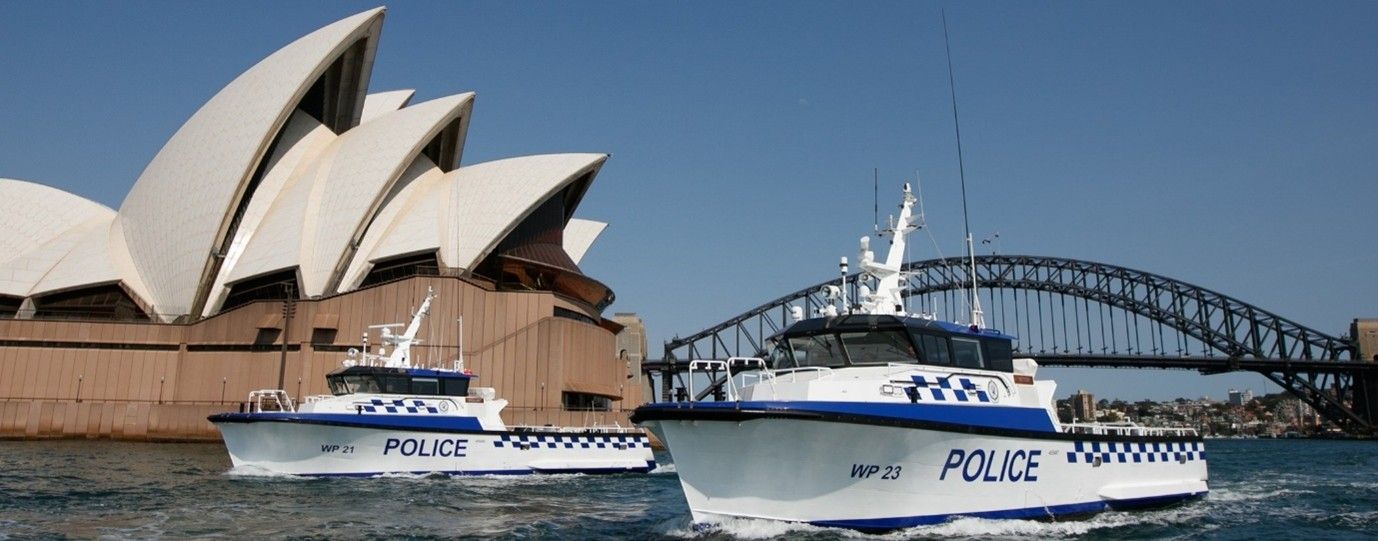 Photo showing 2 police boats on the harbour, with the opera house and harbour bridge behind them.