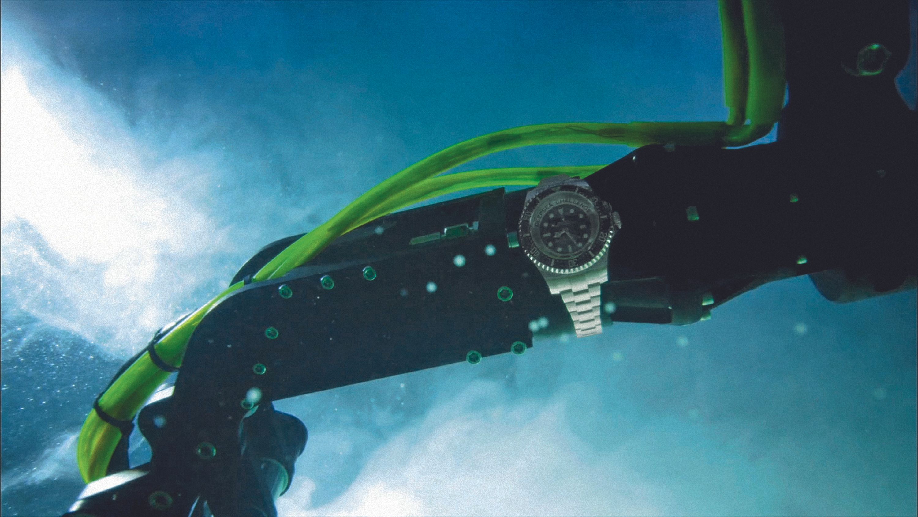 Photo showing a silver watch attached to a robotic arm in the water. 