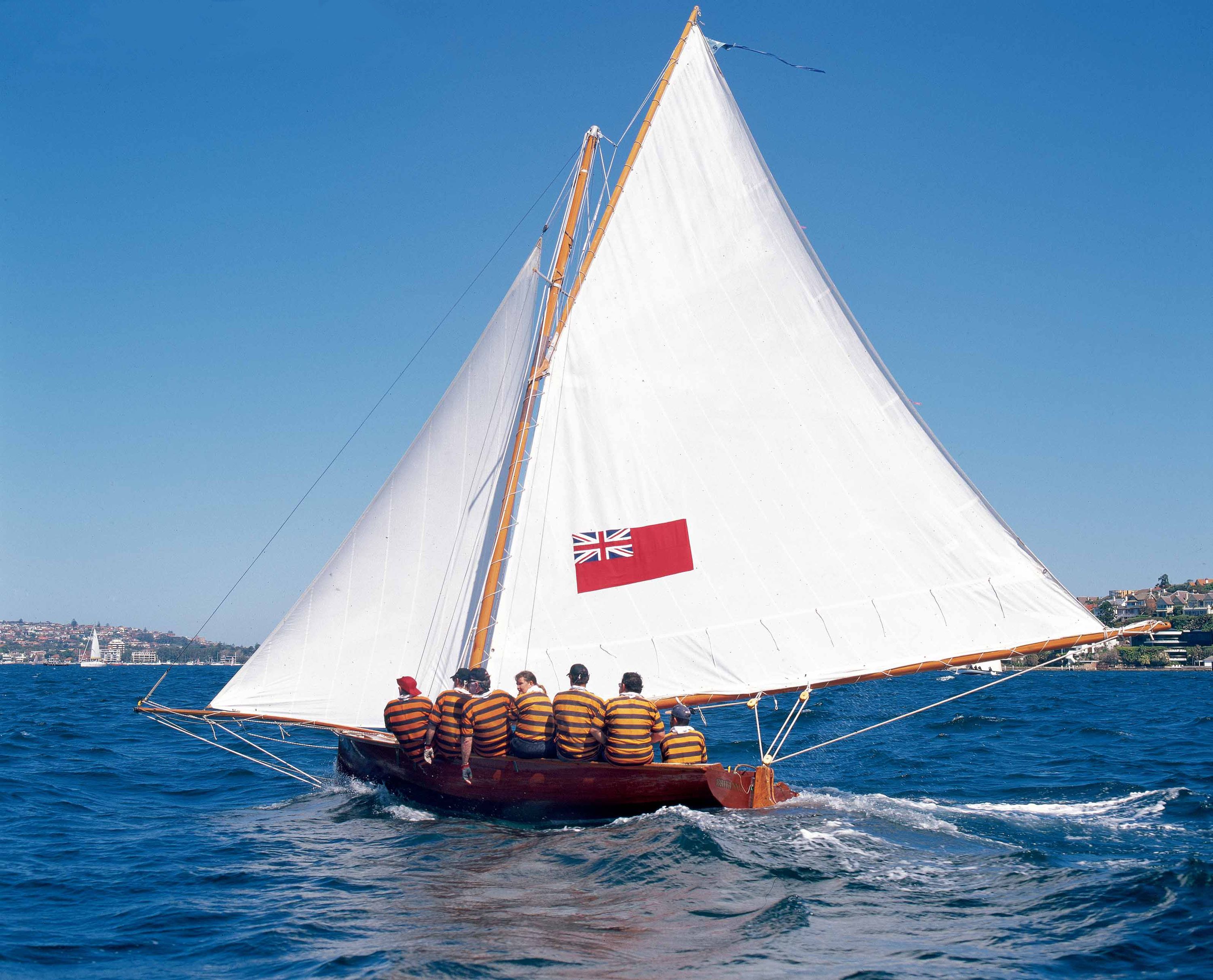 photo of a small sailing boat with white sails.