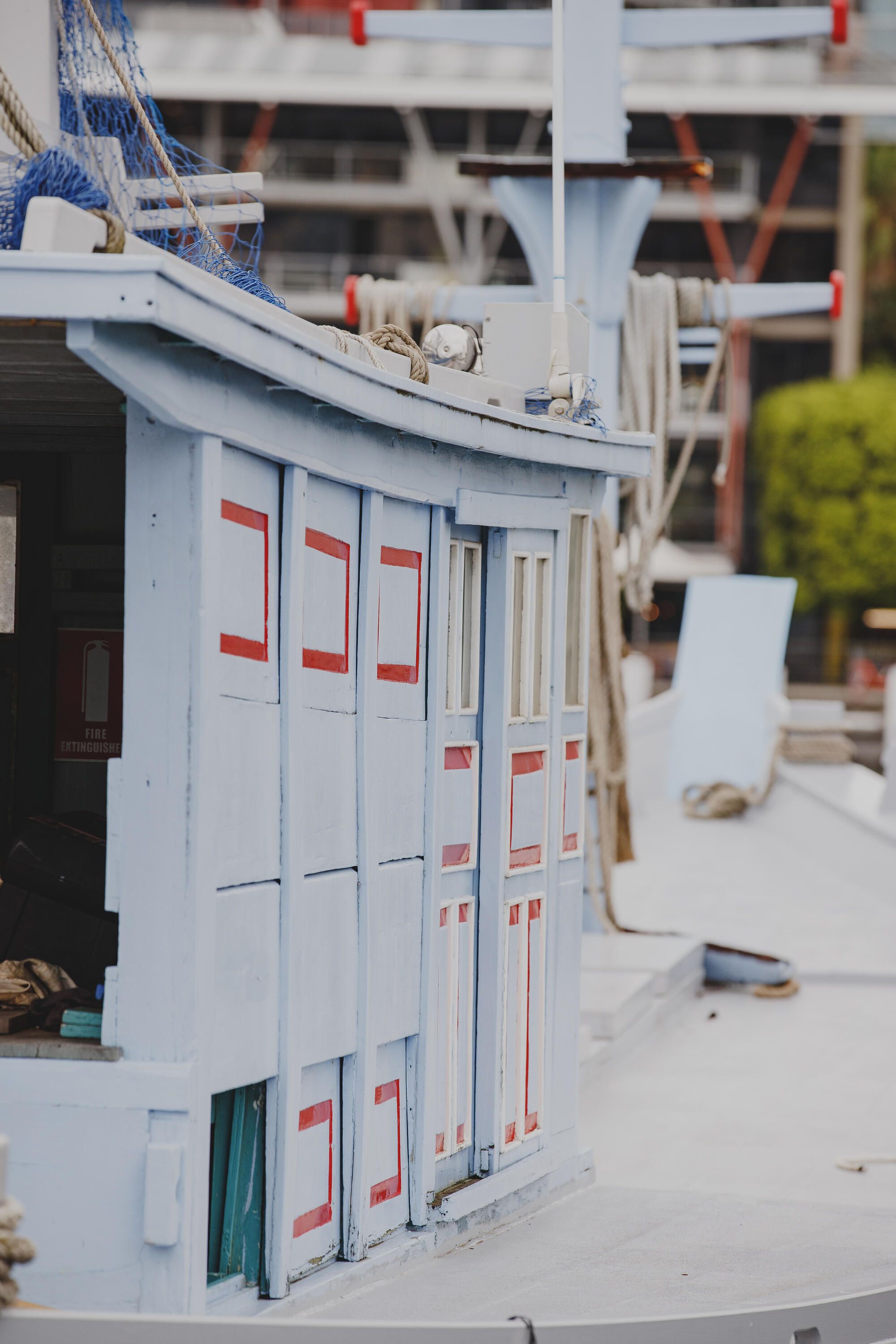 Photograph of a wooden boat showing the side of the cabin painted pale blue and trimmed in red.