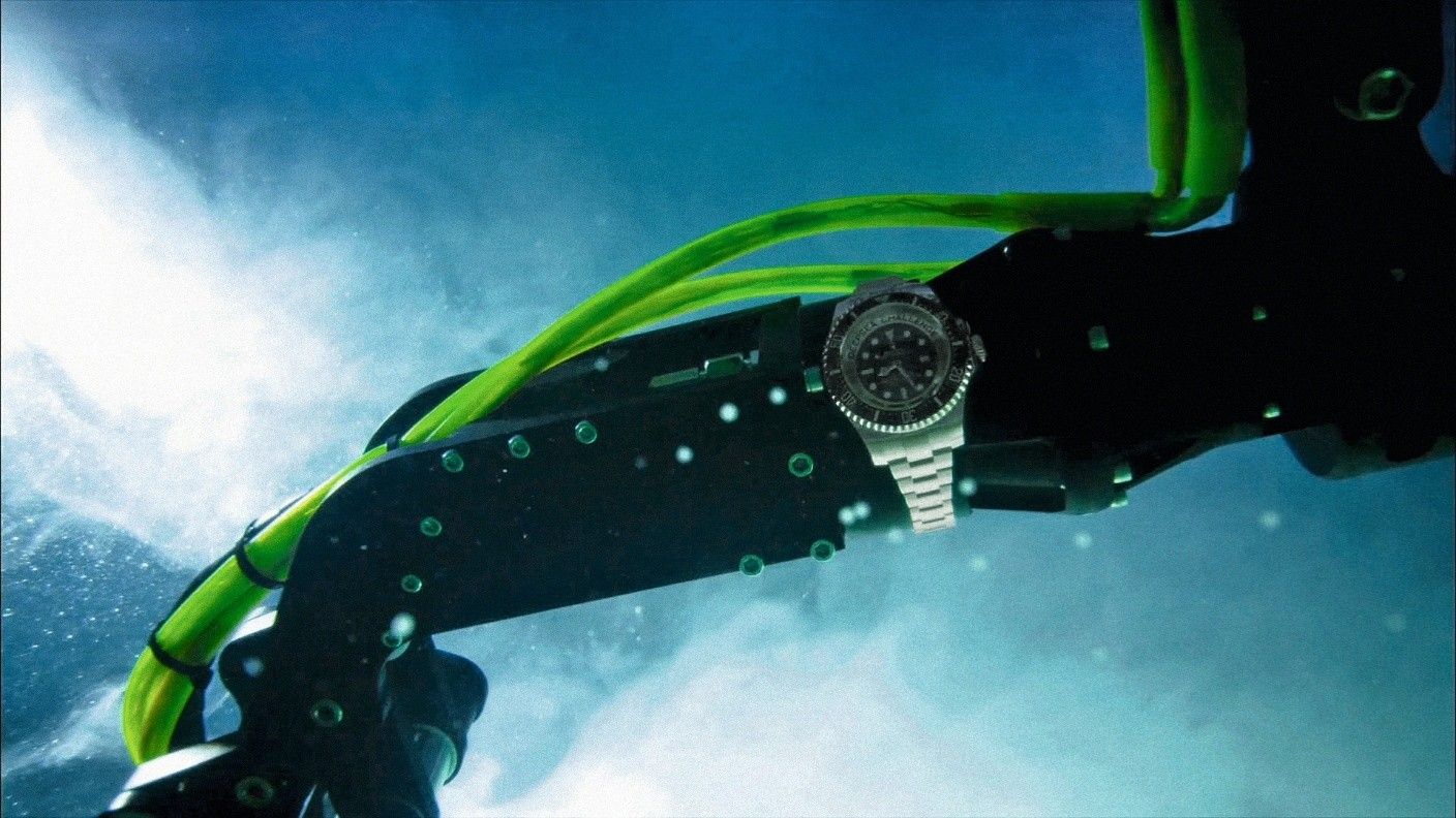 Photo showing a silver watch attached to a robotic arm in the water.