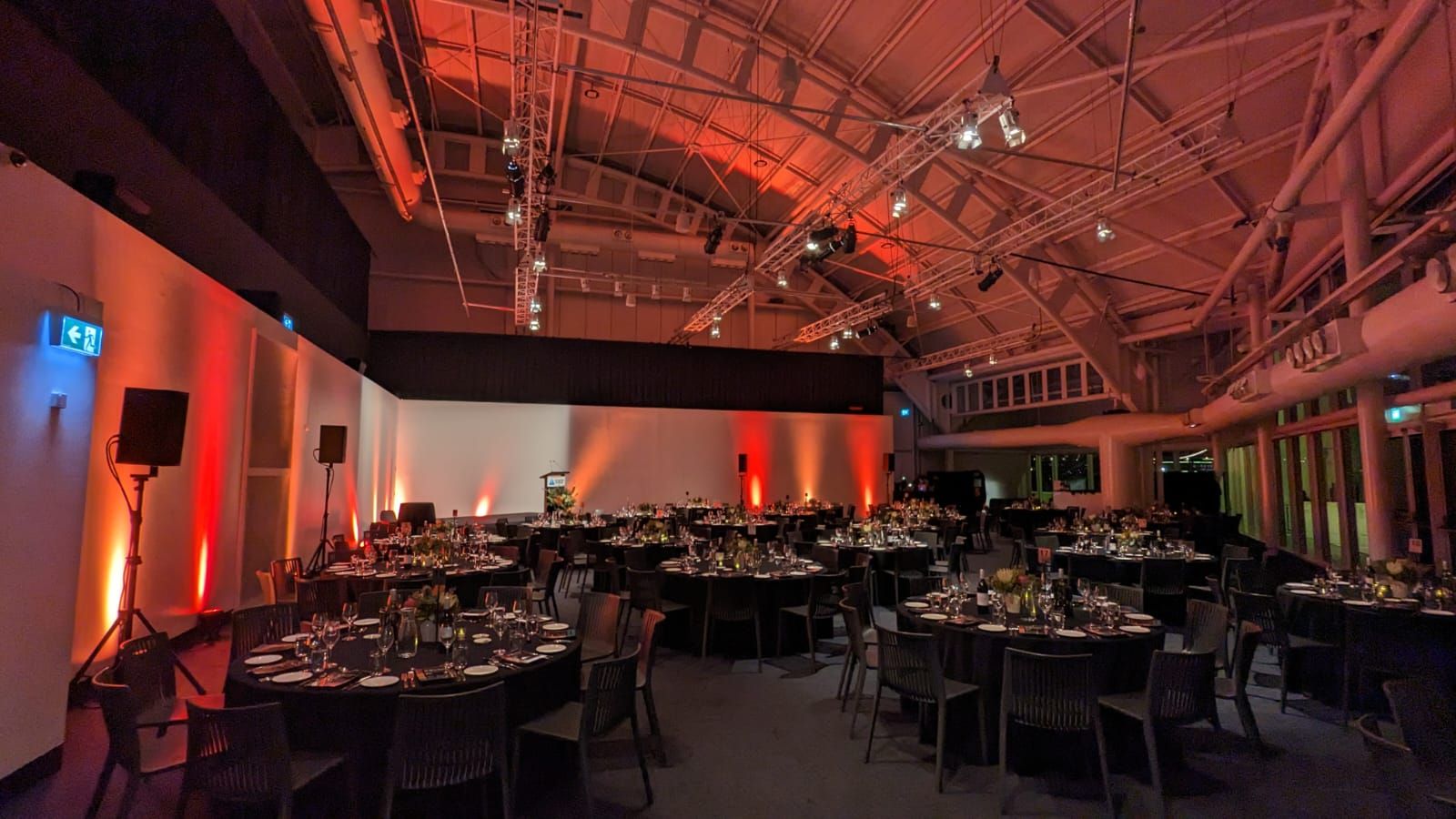 photo of an interior of a large event space, with tables and a red lighting scheme. 