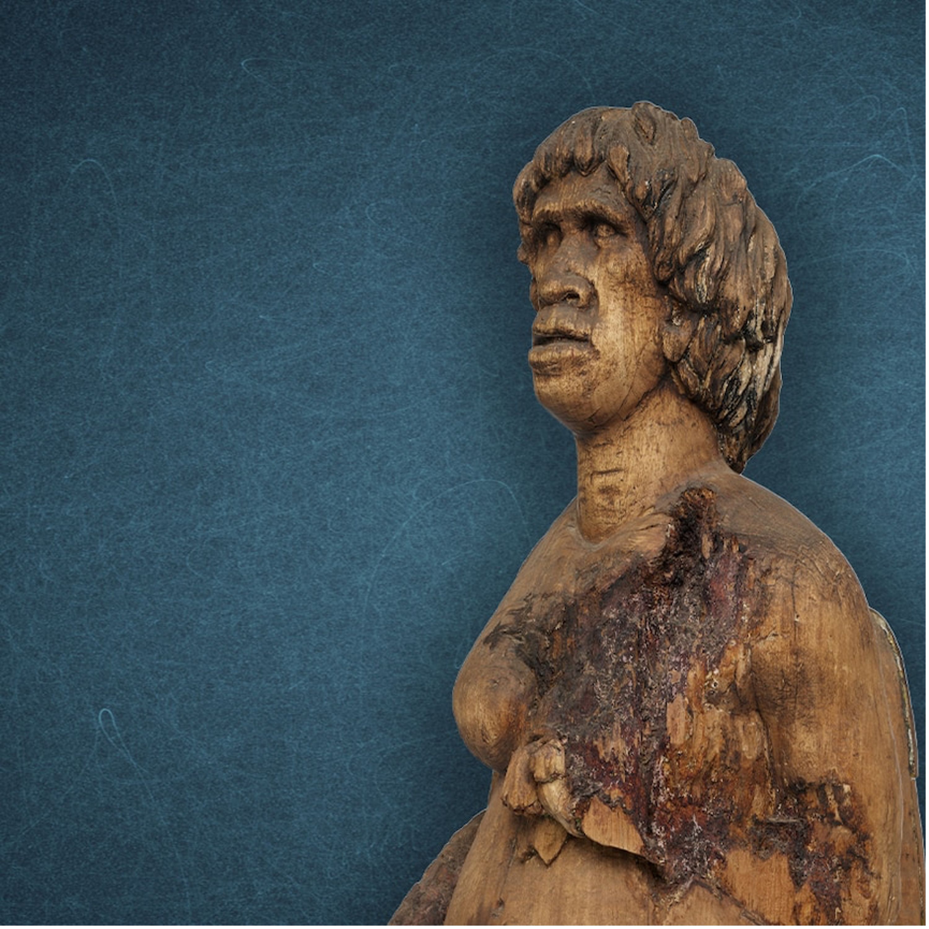 Photo of a wooden sculpture of a woman, on a blue background