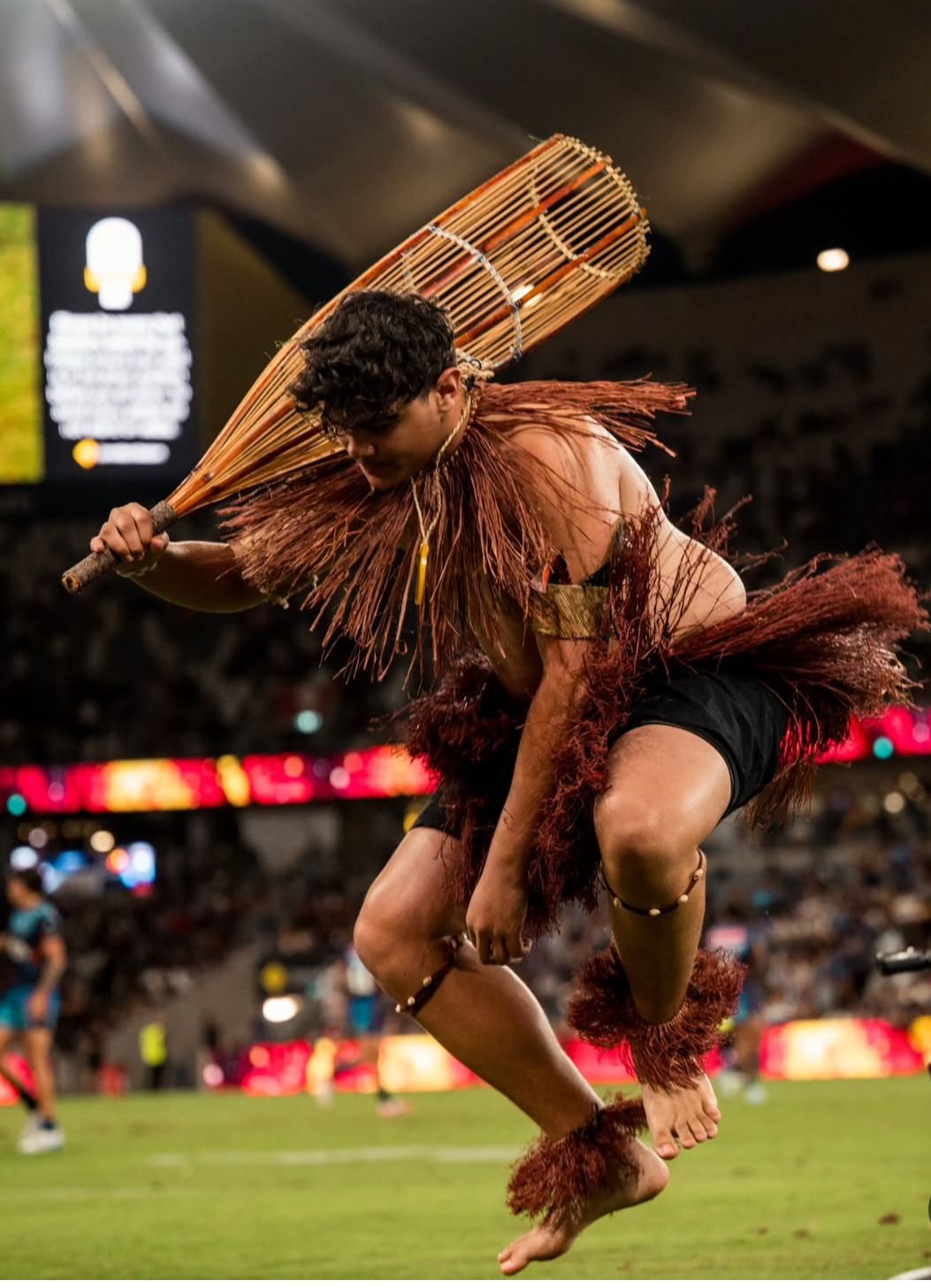 Photo showing a dancer jumping, wearing a grass skirt.