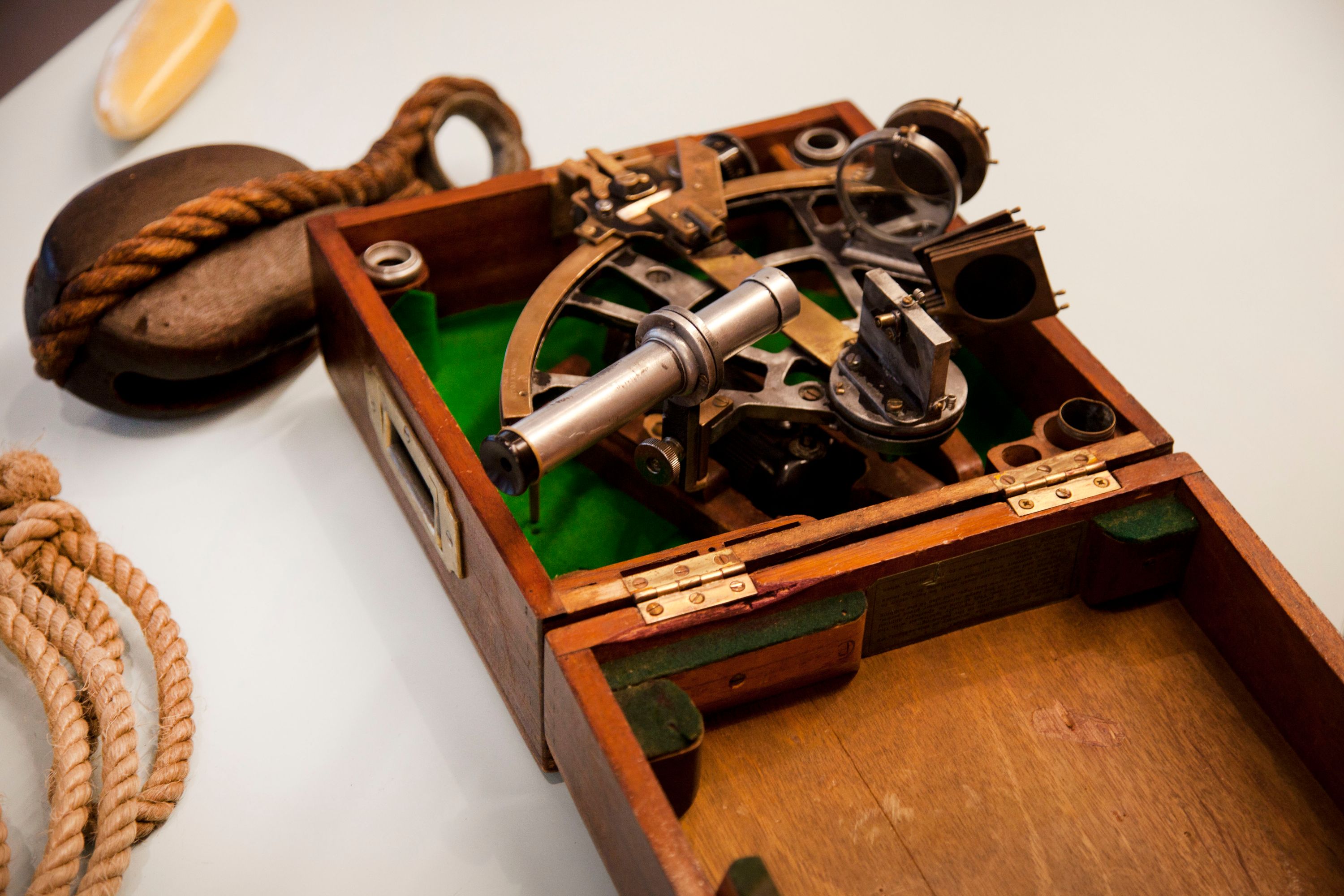 Close up photograph showing a brass sextant in a wooden box.