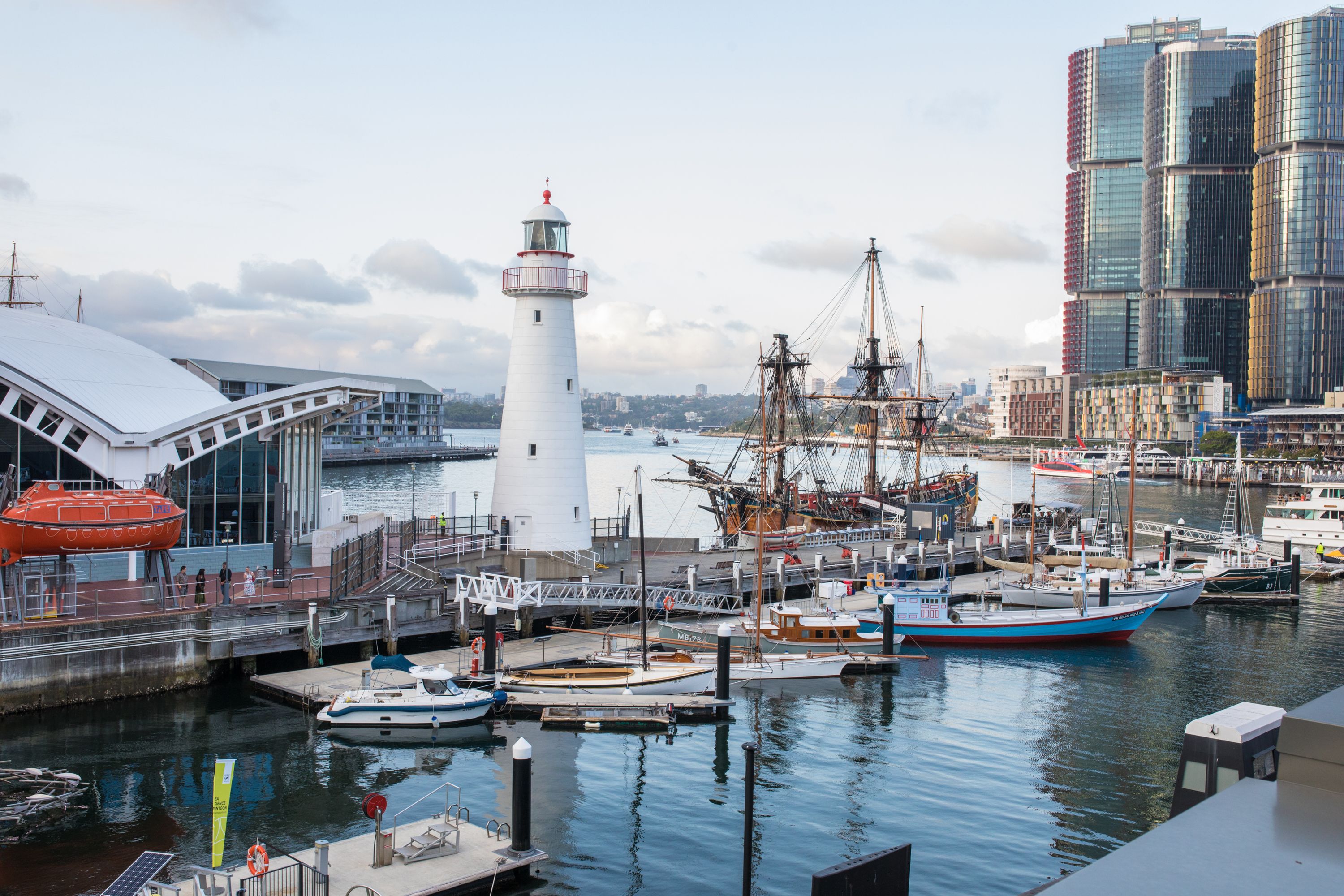 Photo showing an exterior view of the museum showcasing the waterfront surrounding the lighthouse, including the fleet of small vessels on the water.