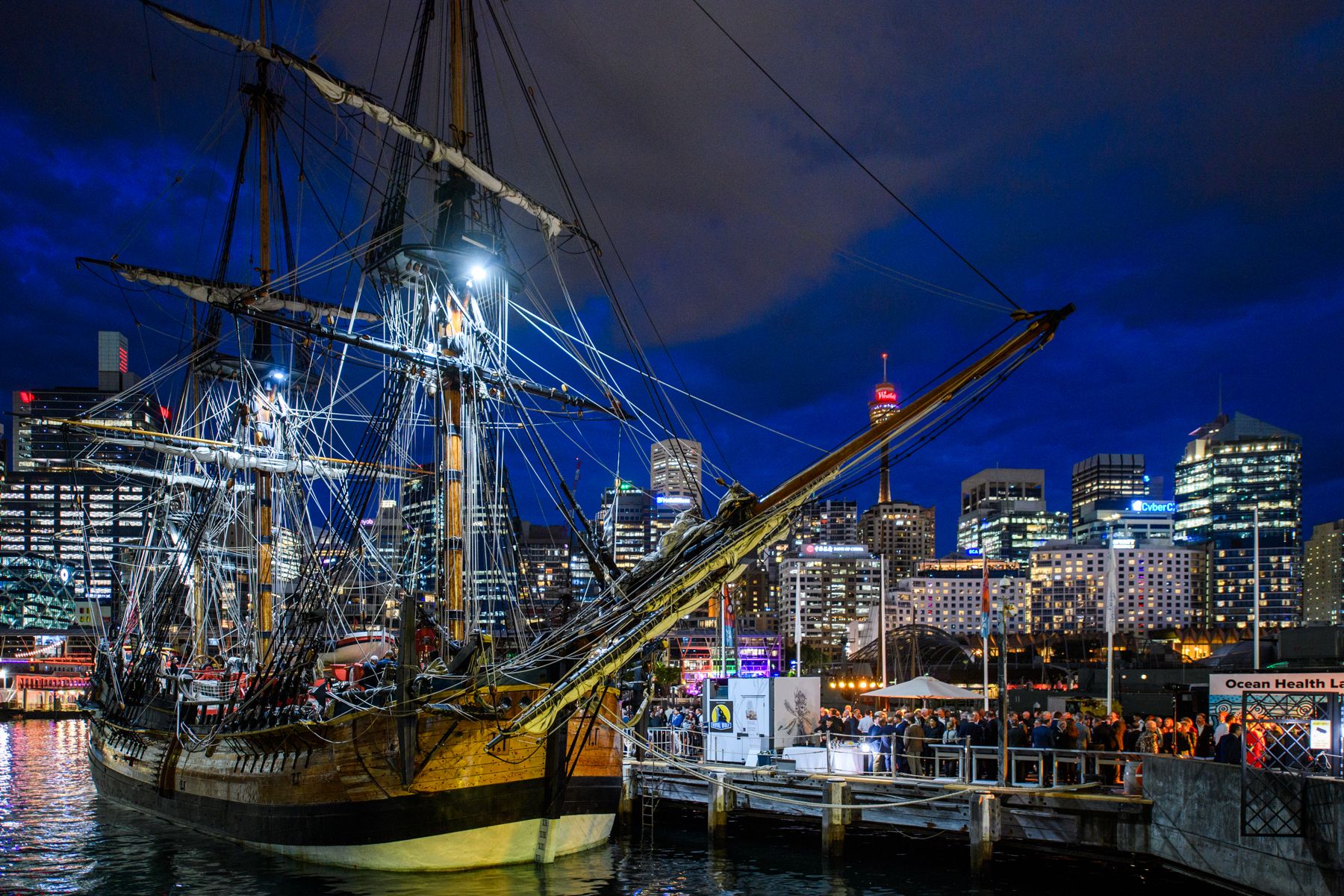  photograph of wooden tall ship endeavour at night with city lights in the background