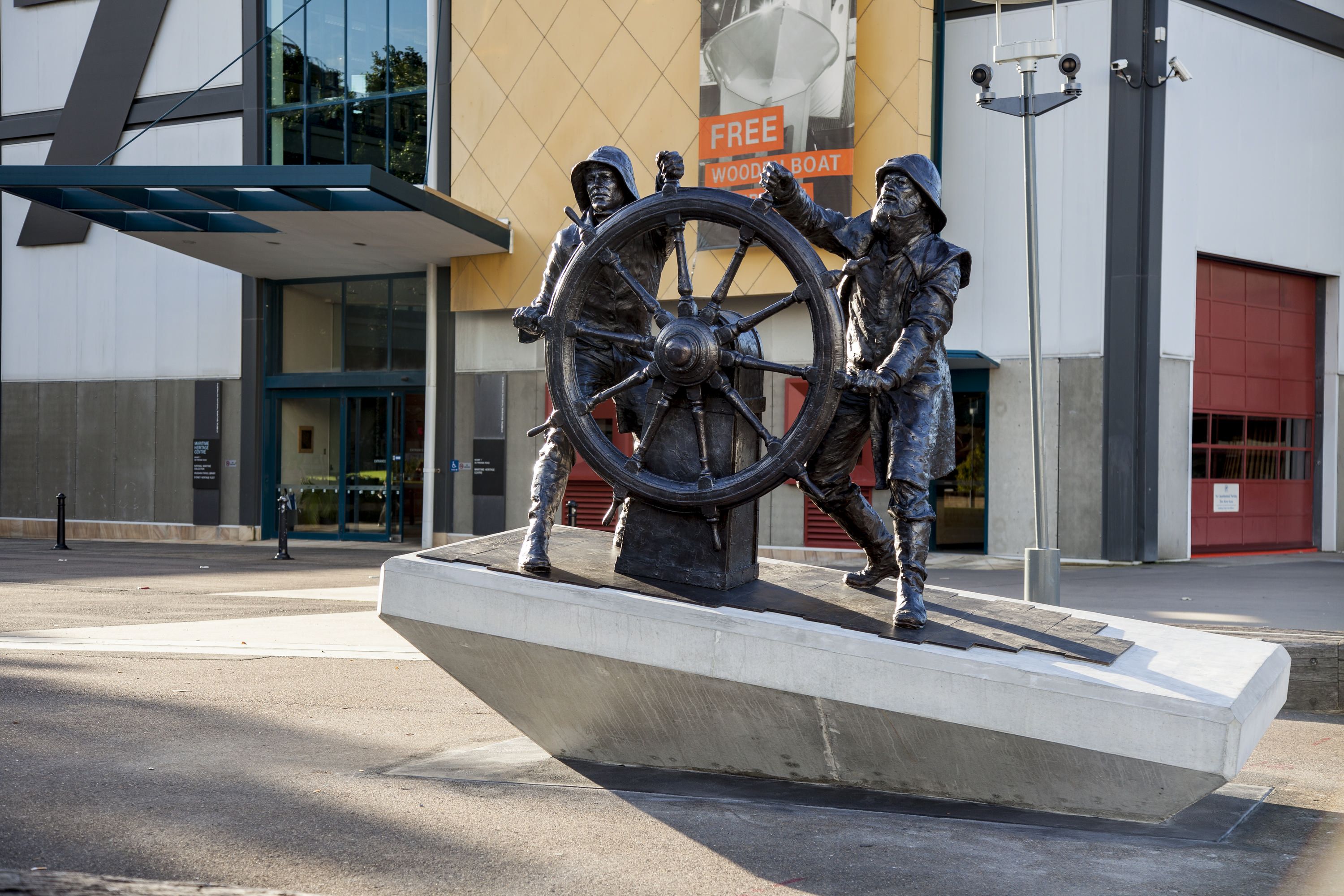 Photo of a bronze sculpture showing 2 two men at the helm of a sailing ship wheel.