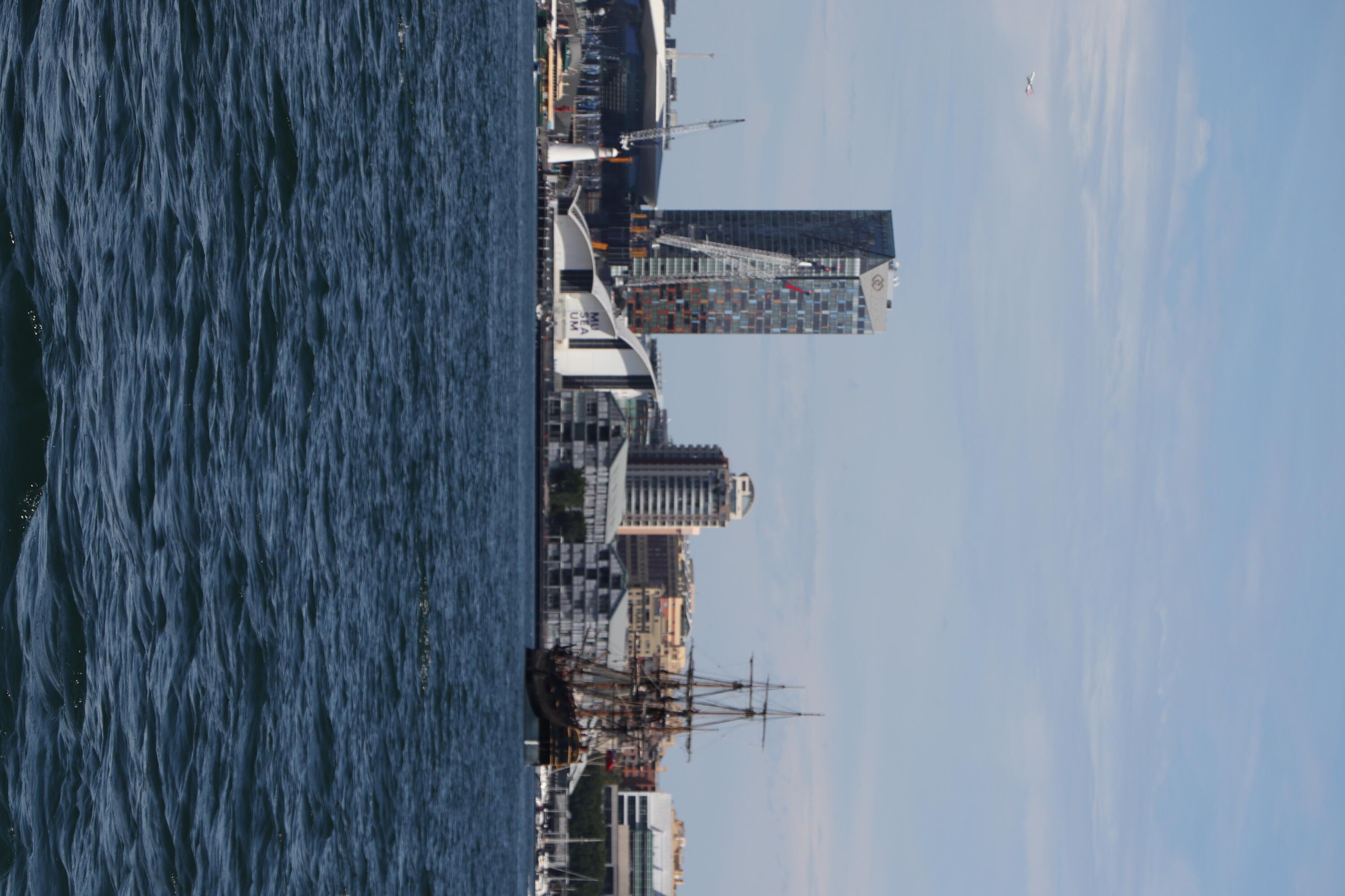 A photo taken of Darling Harbour with the museum building in the background and the tall ship Endeavour sailing towards it.