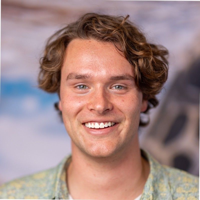 Photo of a man with short, curly hair smiling at the camera.