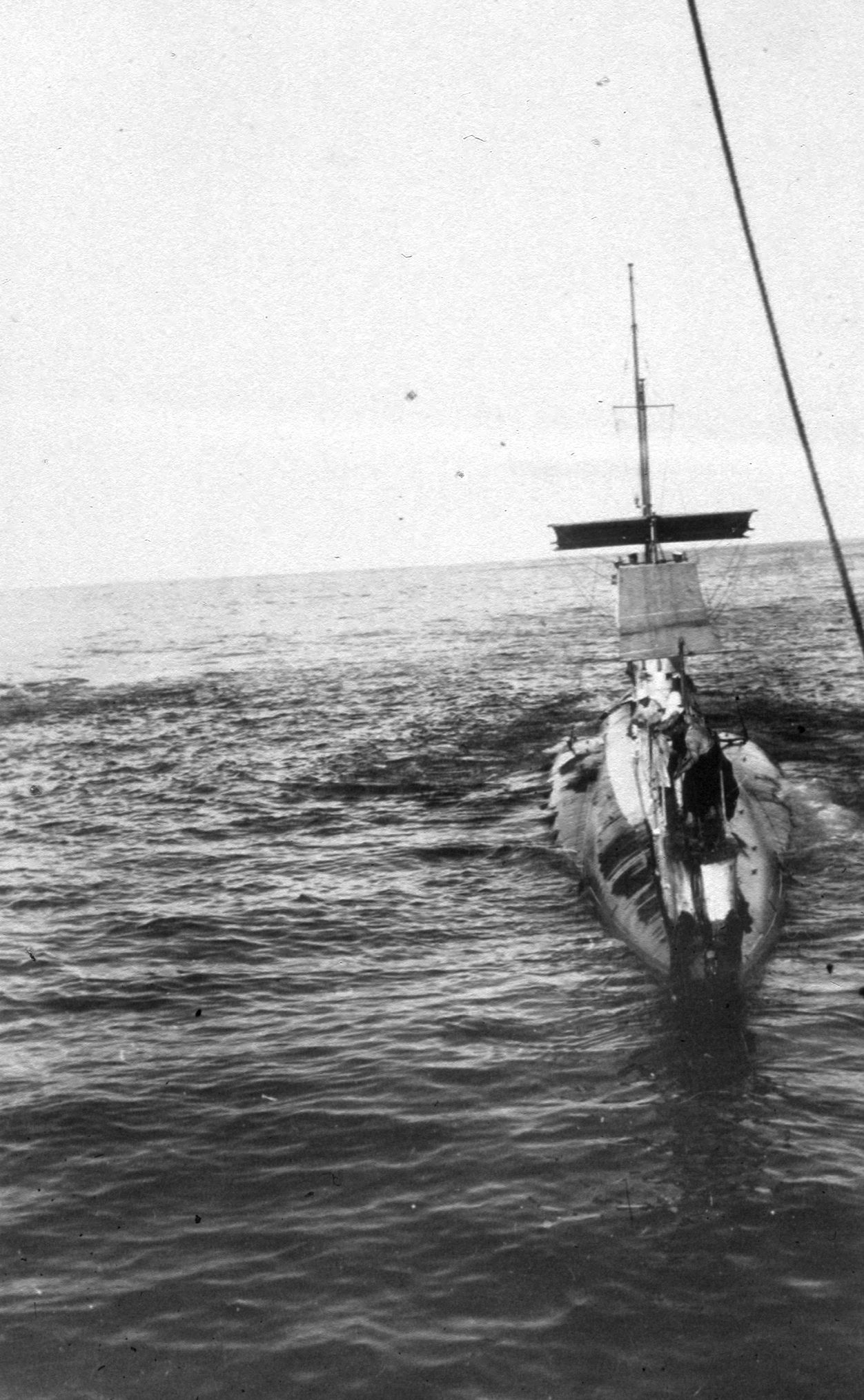 Silver gelatin print, black and white photograph of the AE2 with the awning up, men visible working on deck