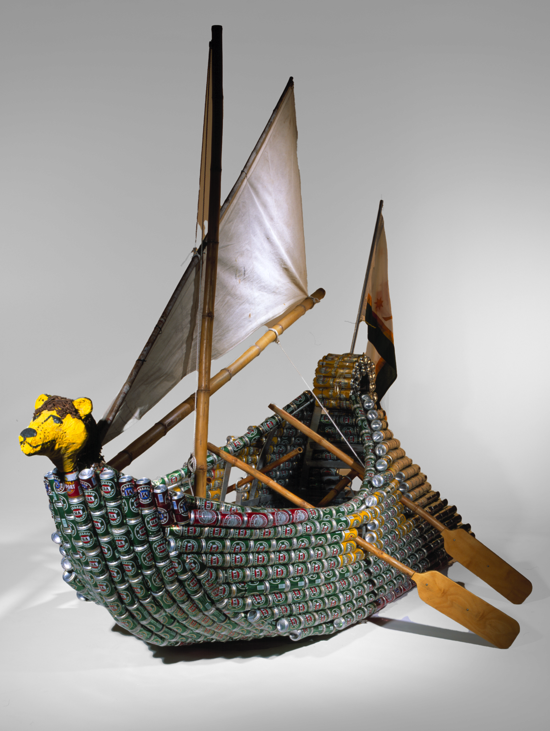 A boat made of beer cans with a lion head and a white sail. 