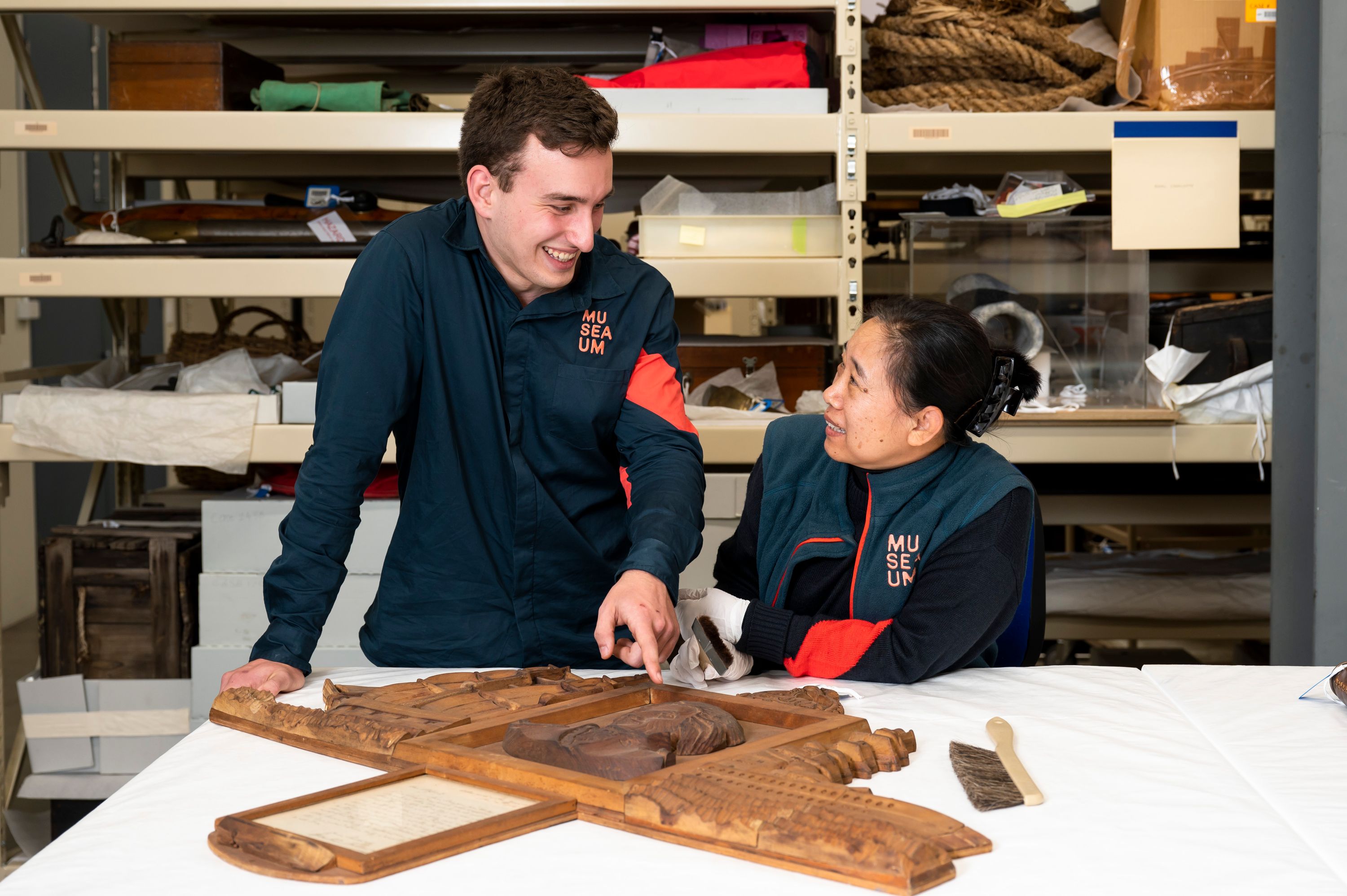 2 museum volunteers, one male one femaile, dusting a collection object in the museum's object stores.