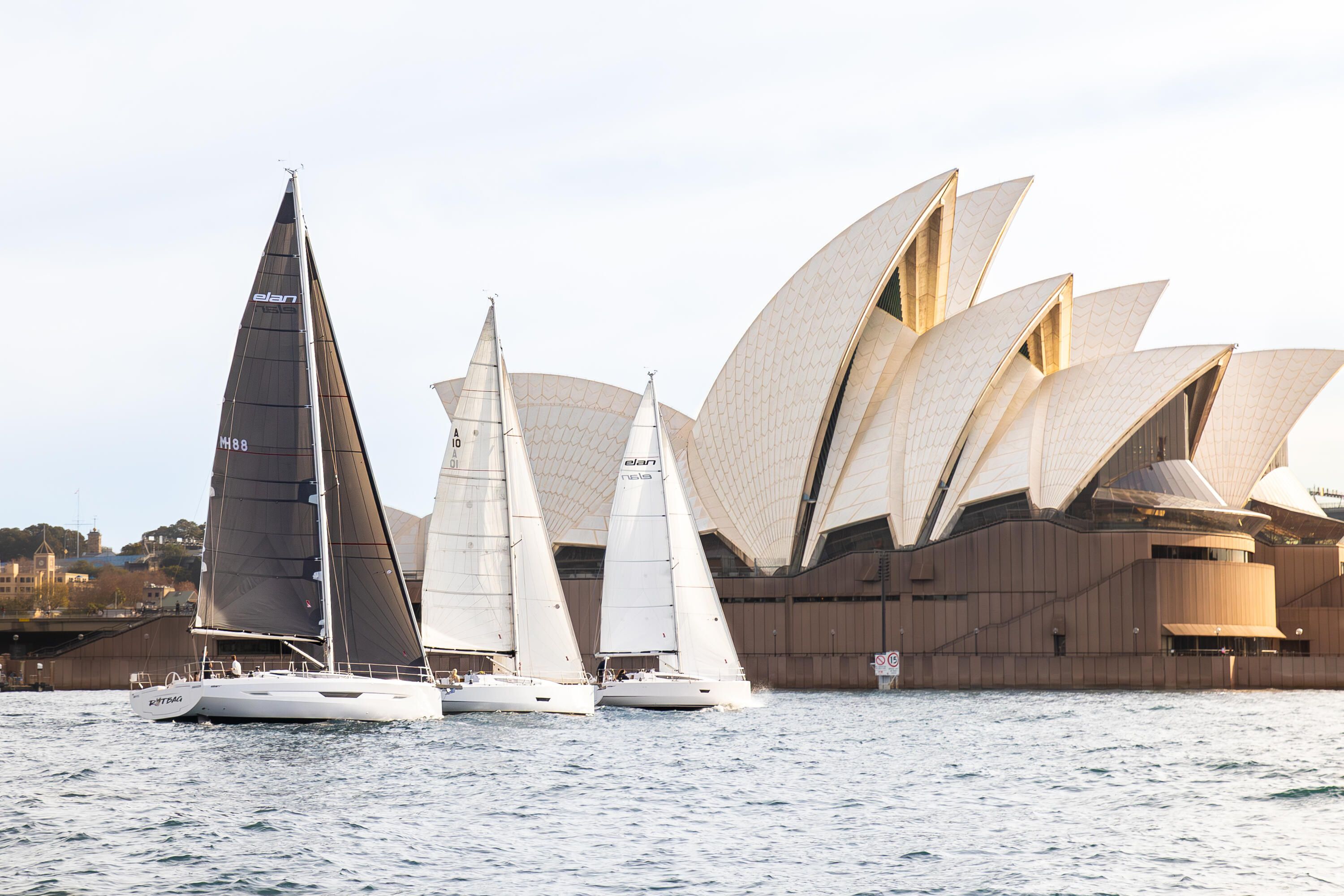 Photo of 3 yachts with their sails up on the water in front of the Sydney Opera House