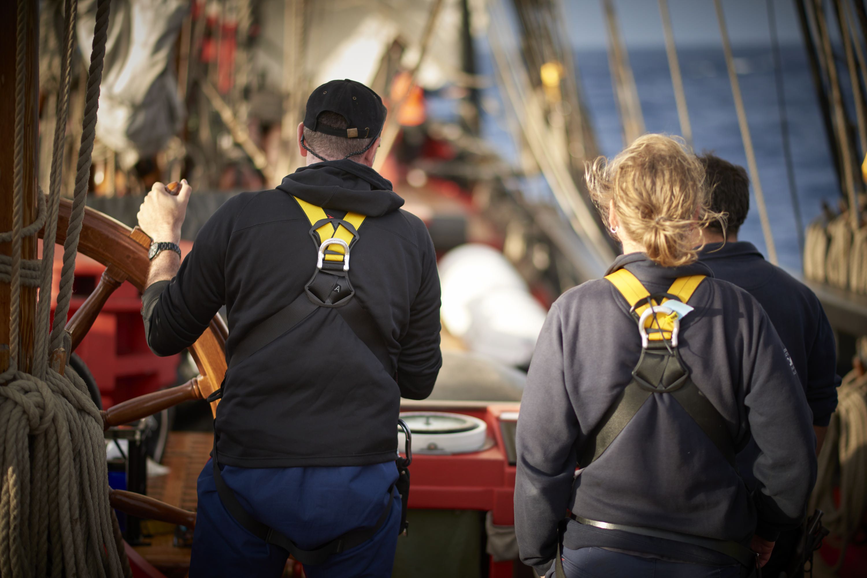 Above deck, crew at the ready sailing towards the horizon.