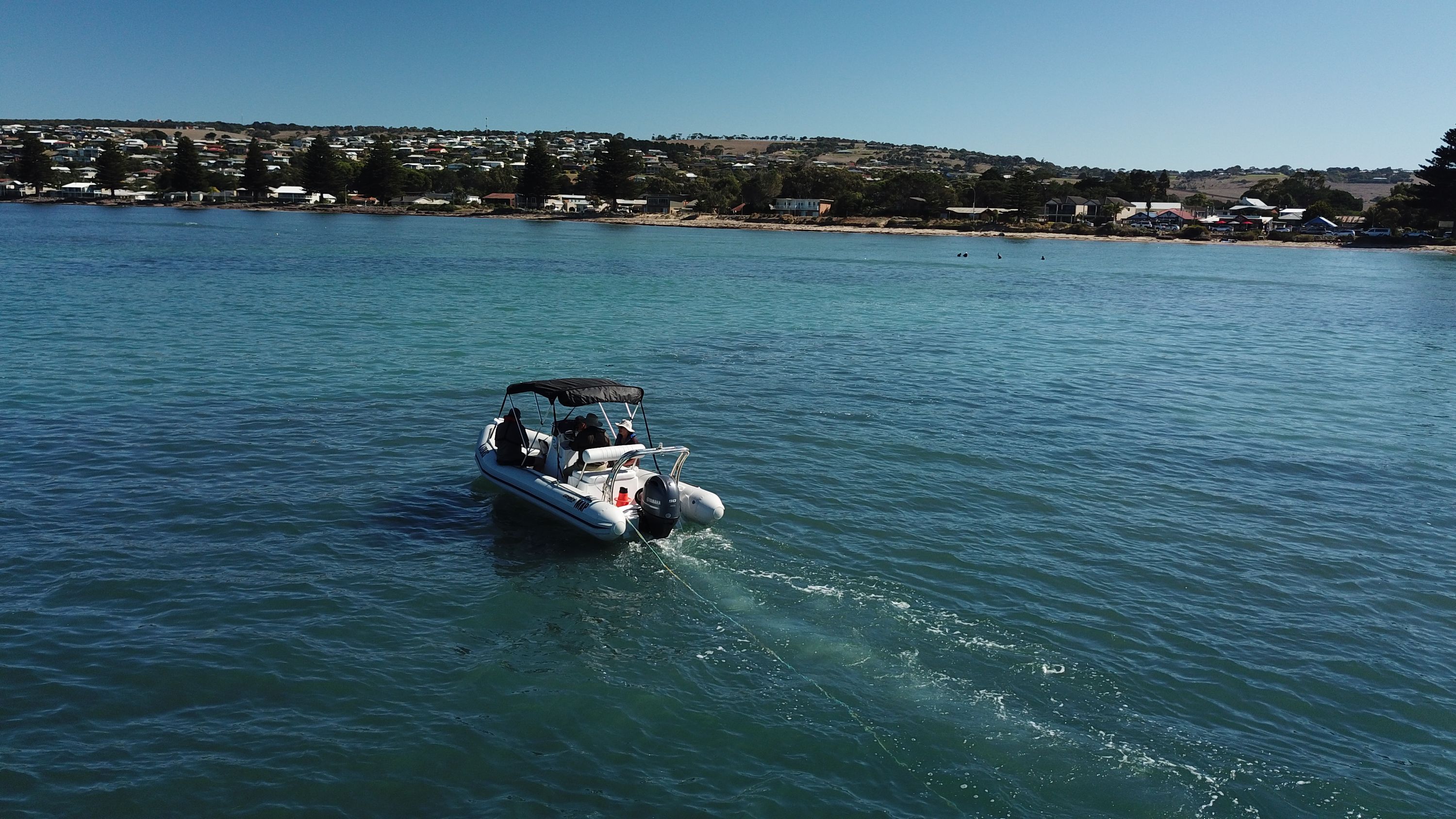 Photograph taken from the air of a small motor boat moving away from the viewer.